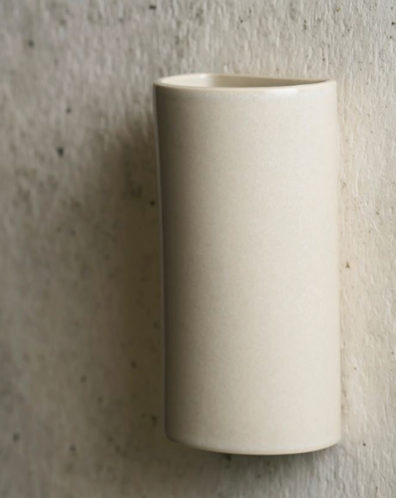 Beige ceramic sconce on a textured gray background