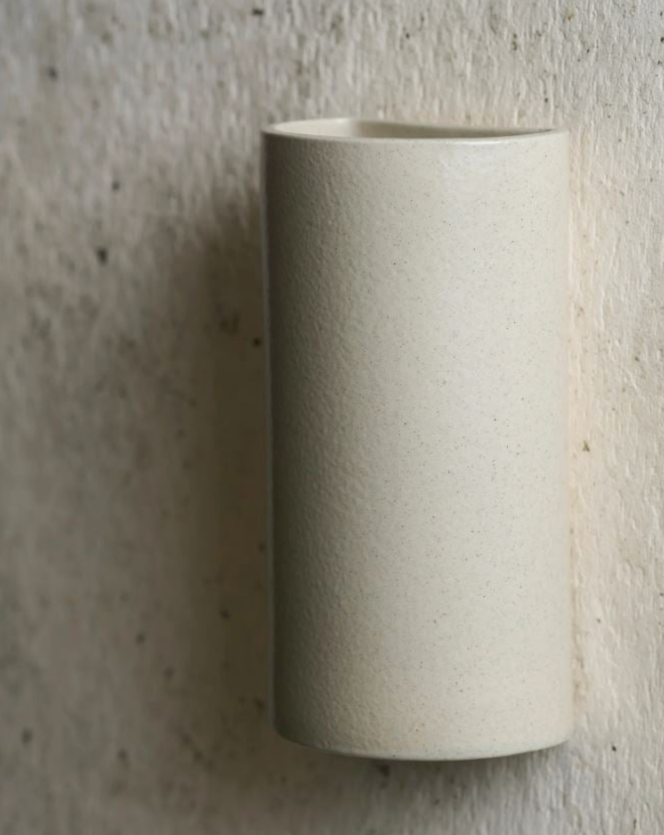Beige ceramic sconce on a textured beige background