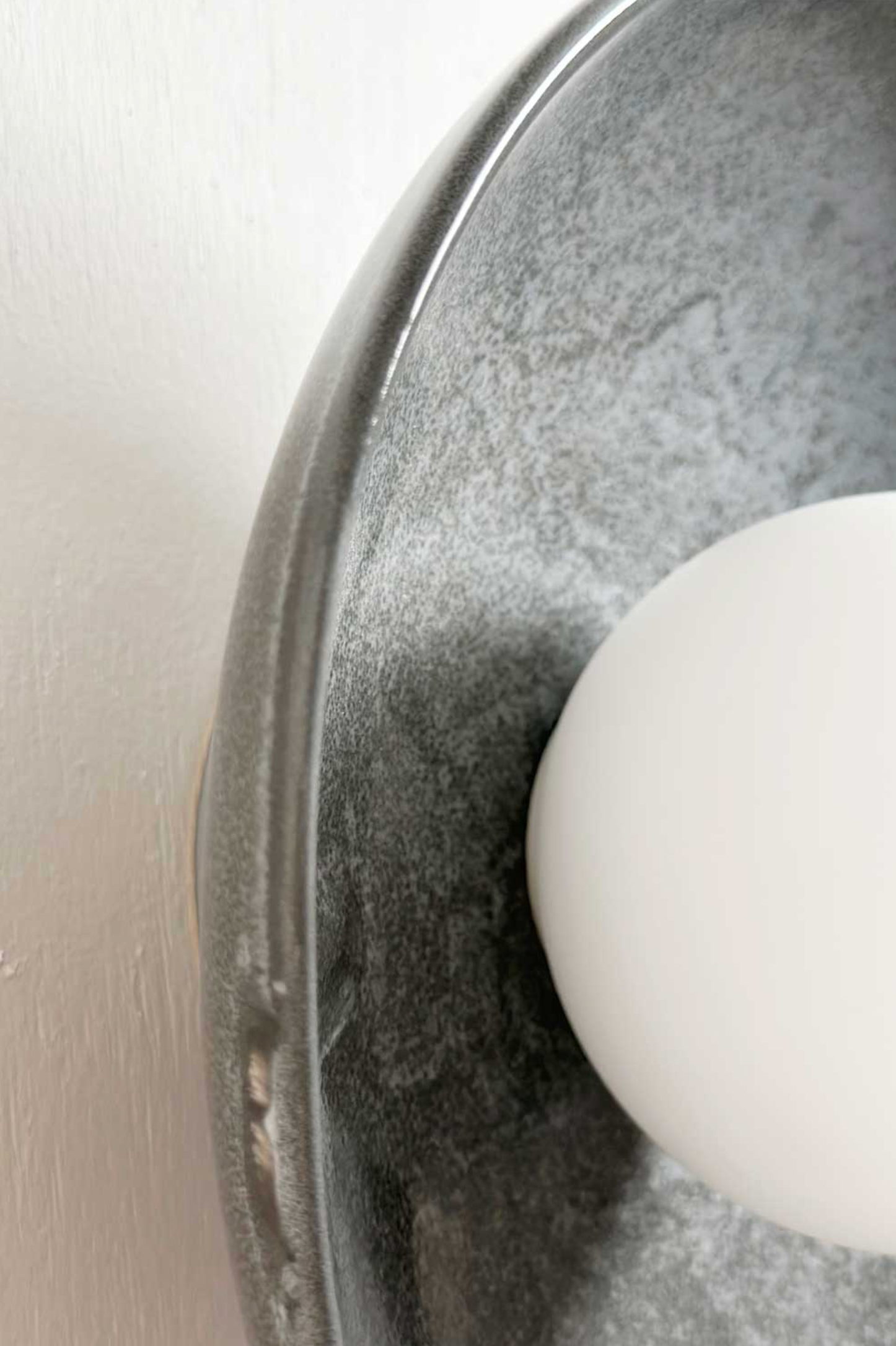 White orb light on a ceramic plate with a blurred neutral background