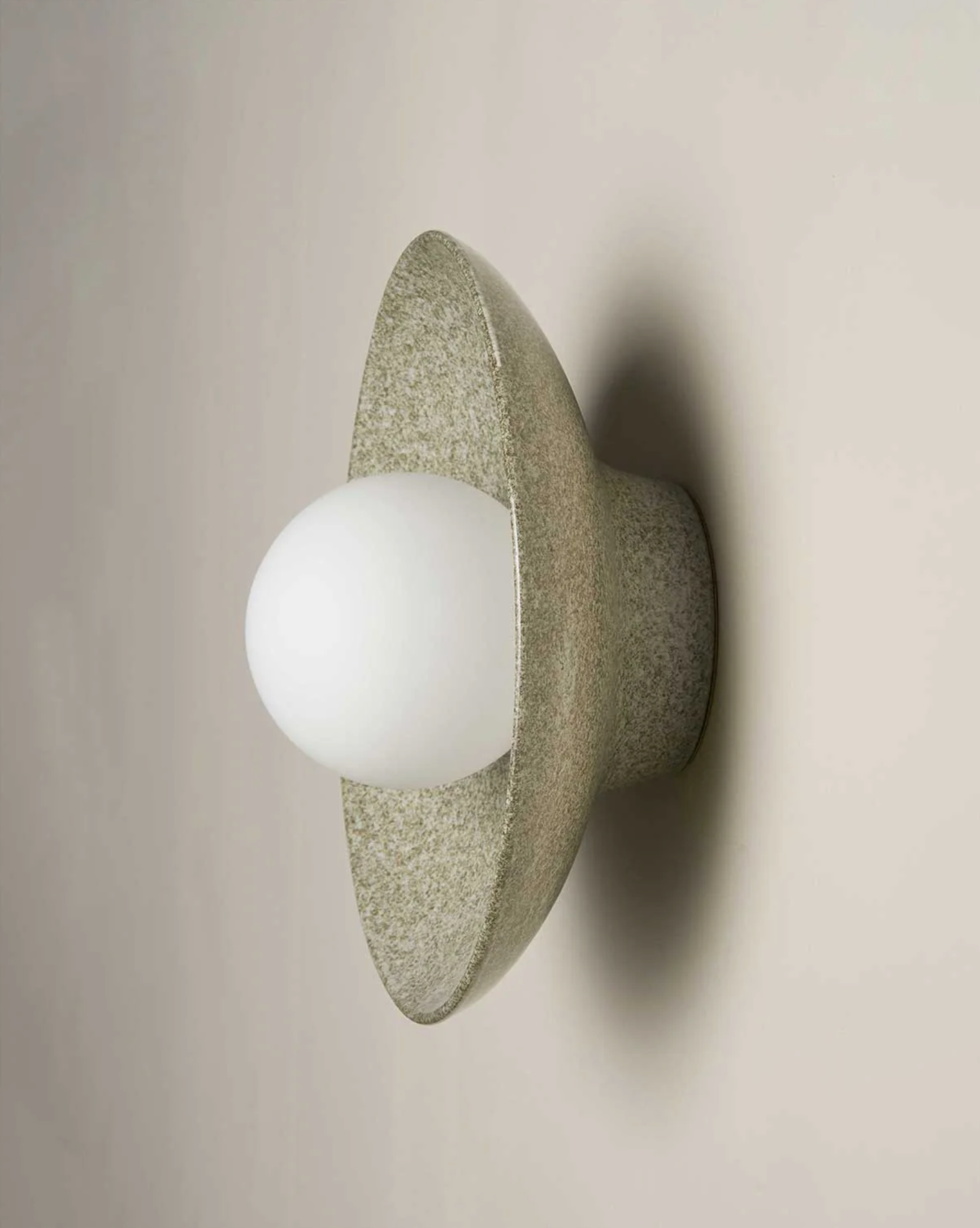 Wall-mounted light fixture with a textured stone-like finish on a plain background