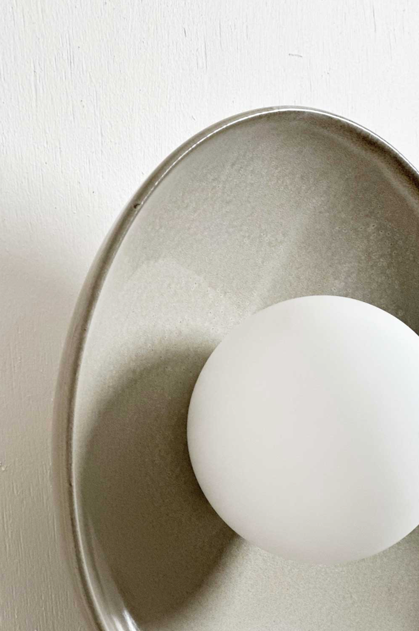 Close-up of a white light orb light on a ceramic dish on a beige wall
