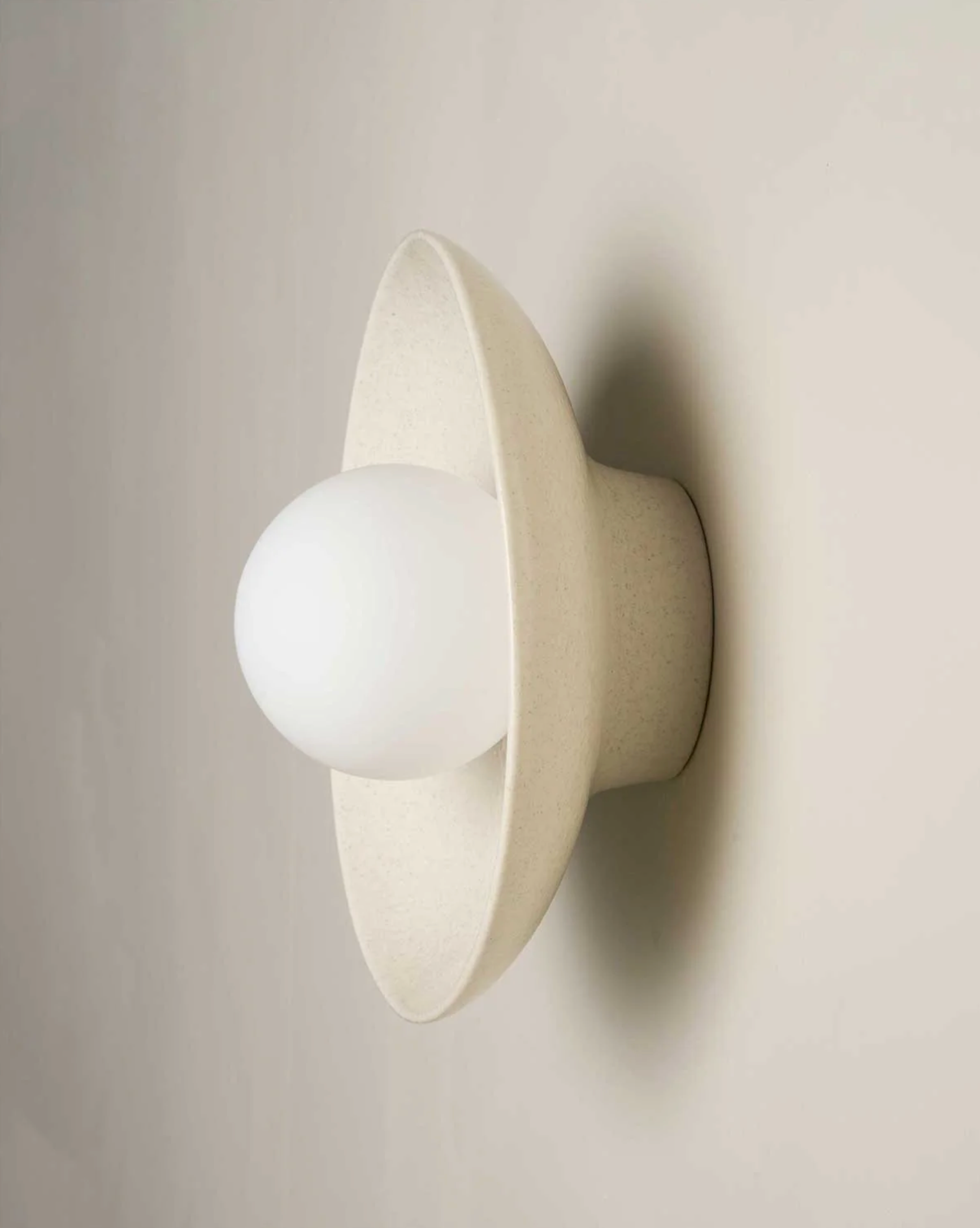 White ceramic wall-mounted lamp with a spherical bulb on a plain background