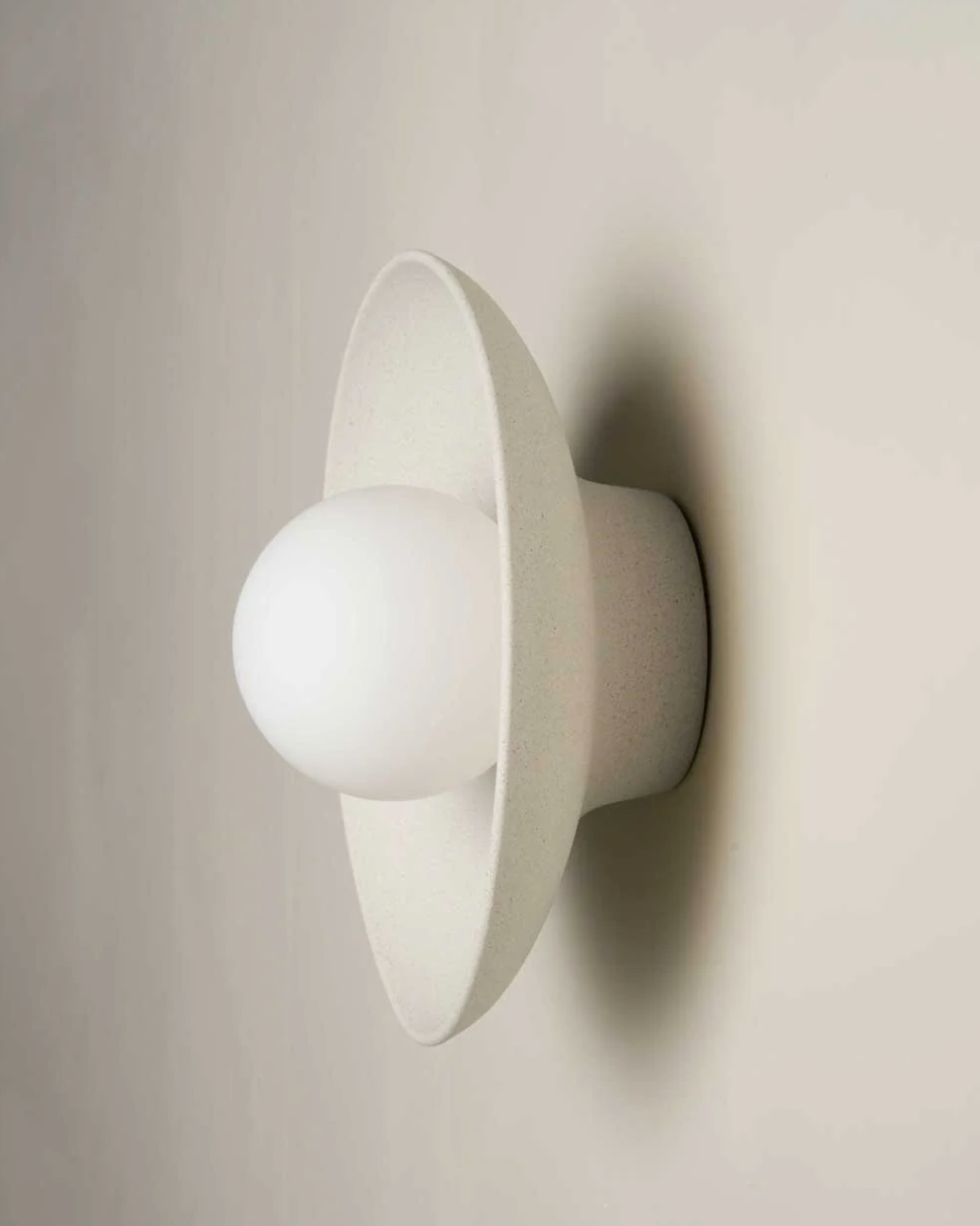 White wall-mounted ceramic wall light fixture on a plain wall