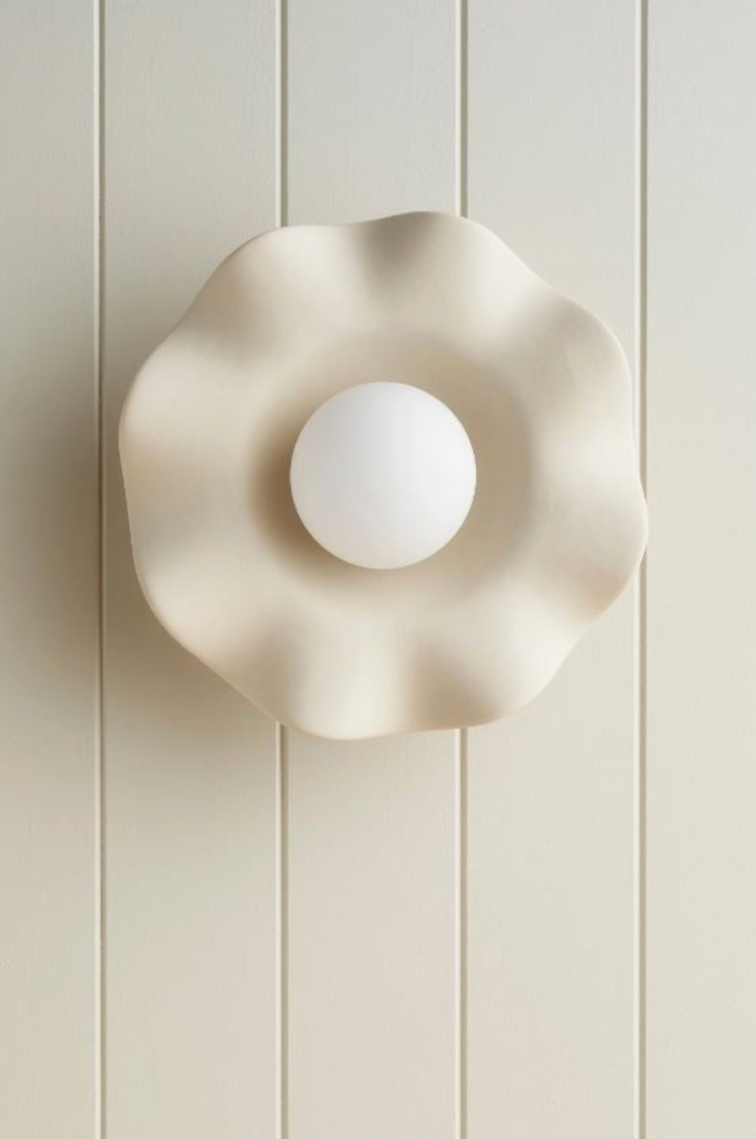 Decorative ceramic wall light fixture on a white panelled wall