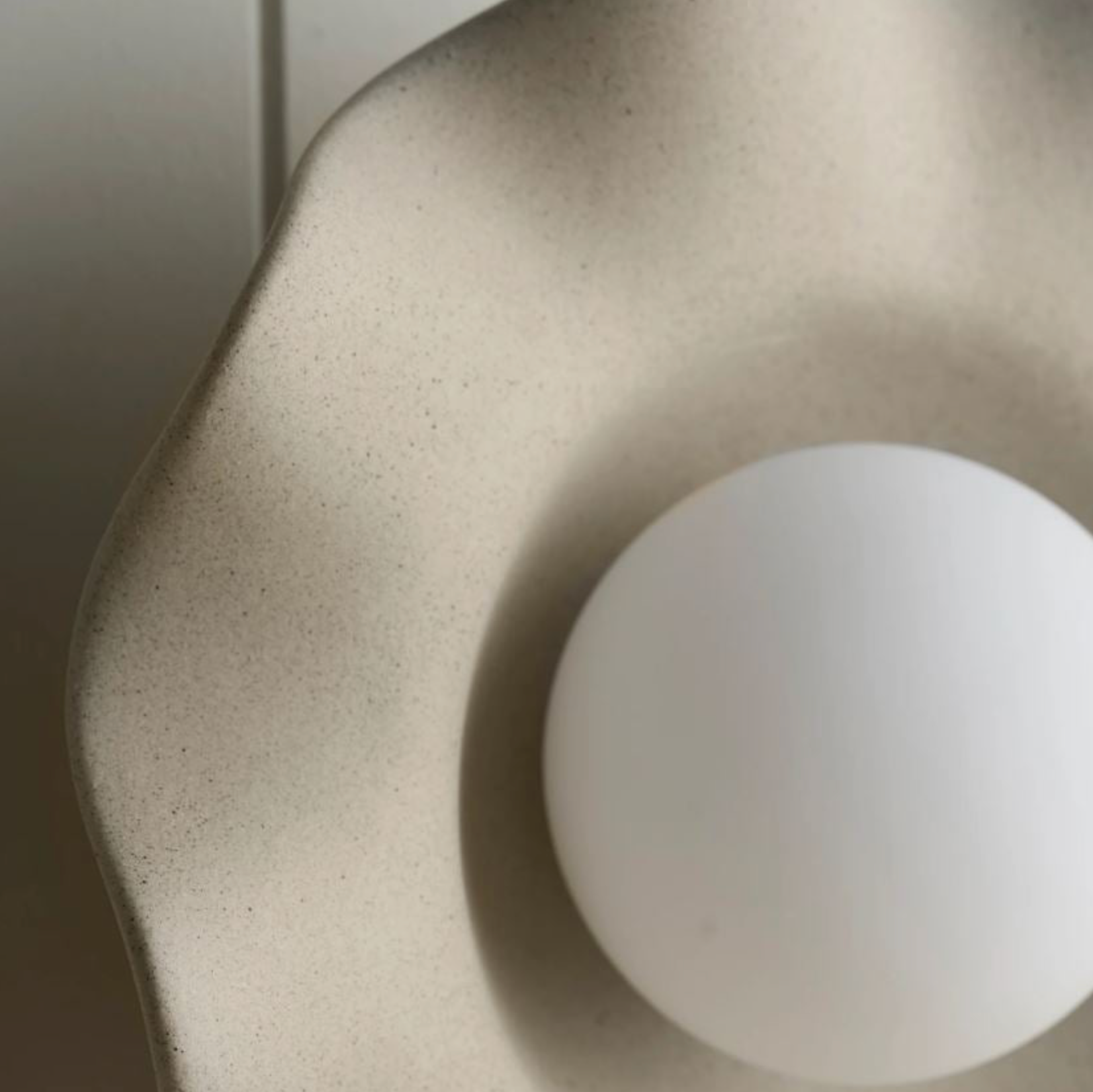 Close-up of a textured ceramic beige bowl with a white ball inside