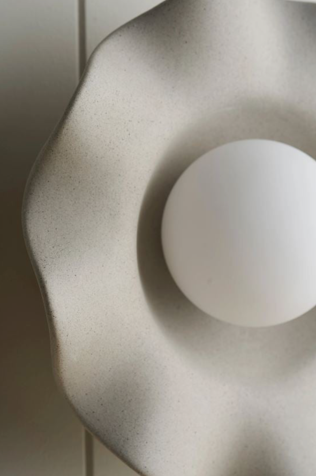 Close-up of a textured ceramic wall light with a smooth sphere inside.