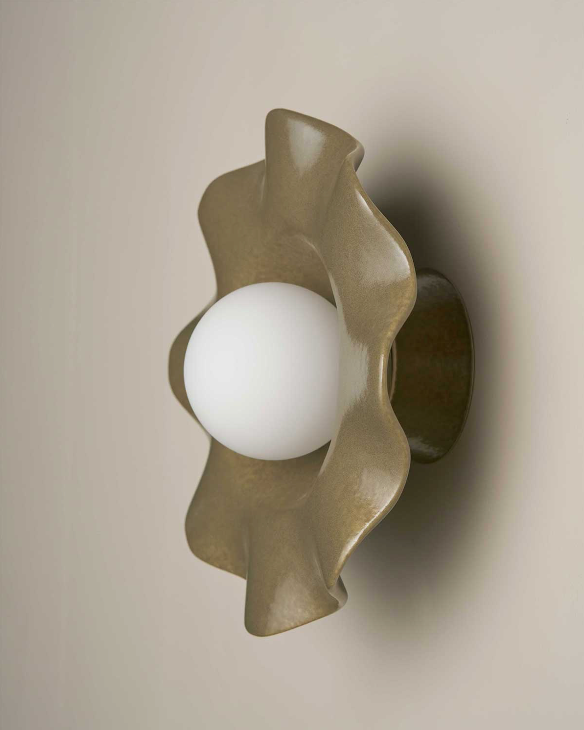 Decorative ceramic wall sconce with a wavy design on a beige background