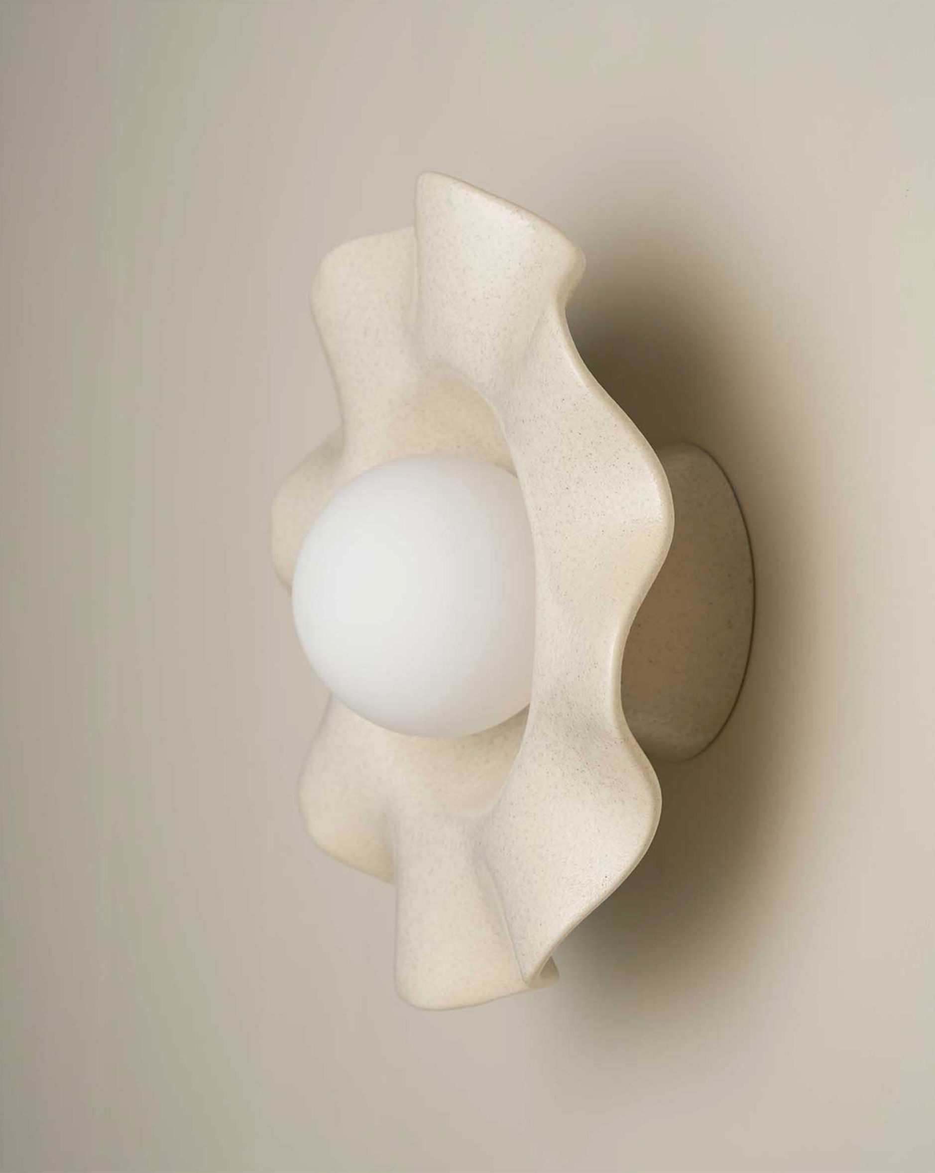 Wall-mounted light fixture with a wavy design on a neutral background