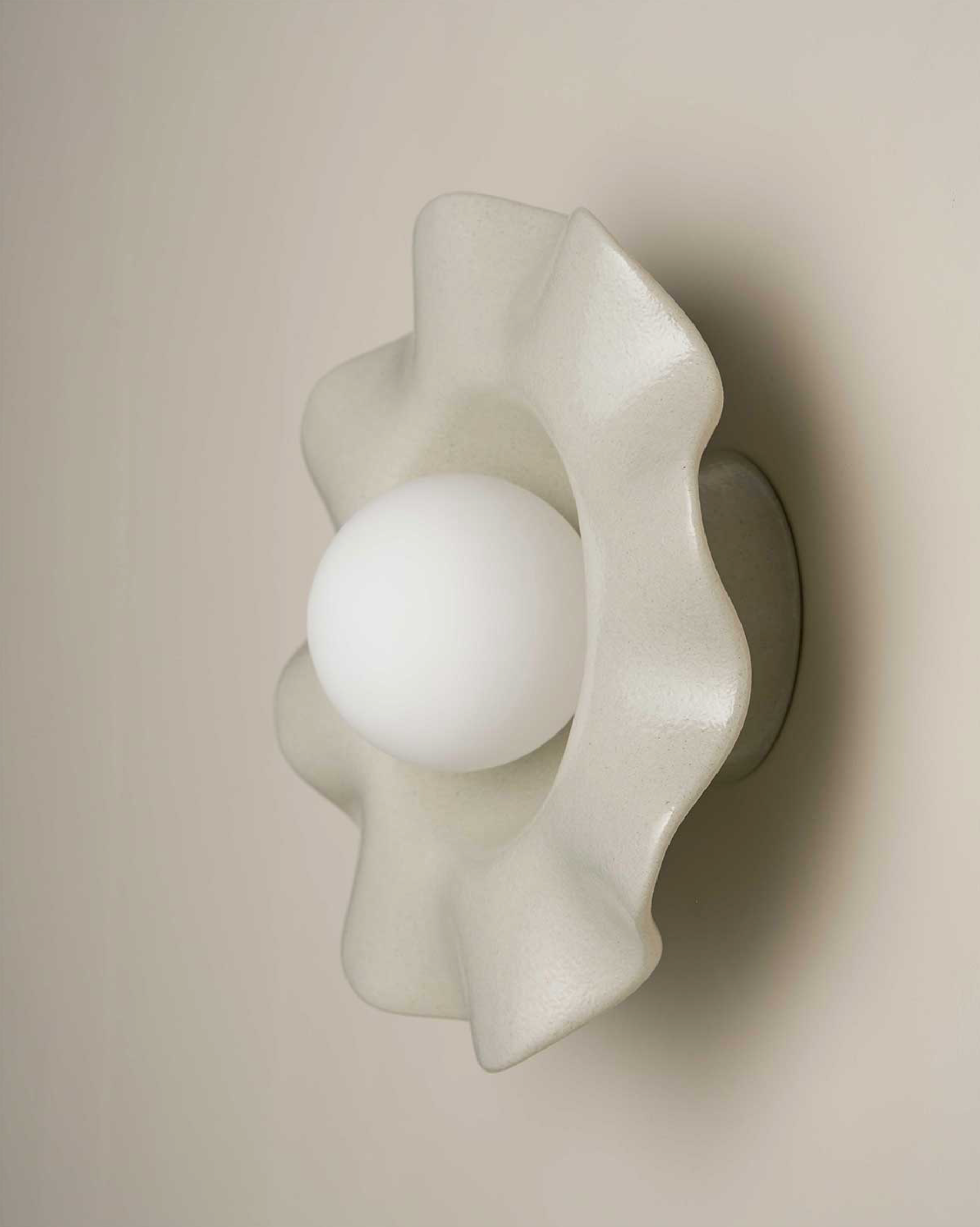 White ceramic wall sconce with a unique design on a beige background