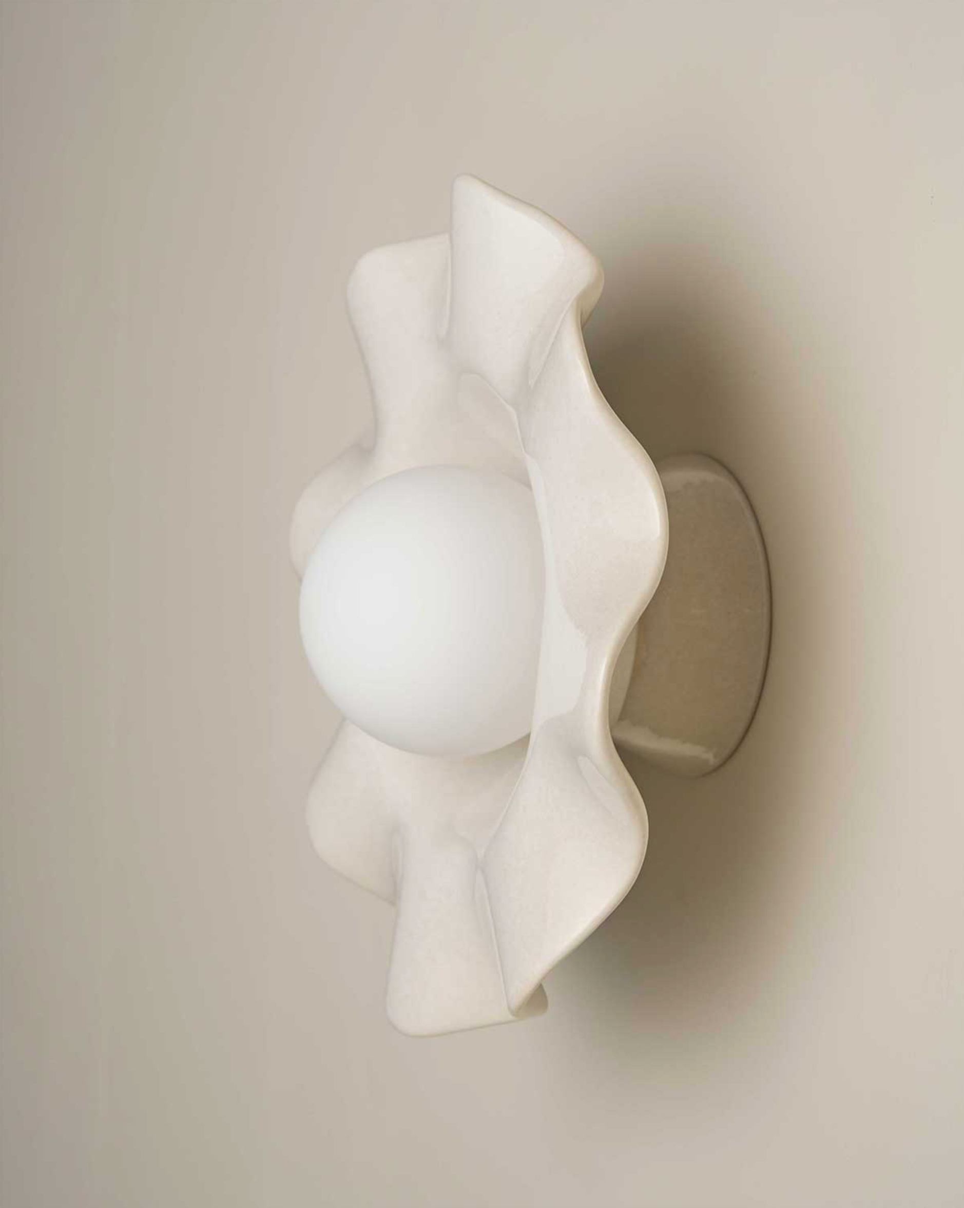 White ceramic wall-mounted light fixture on a beige wall