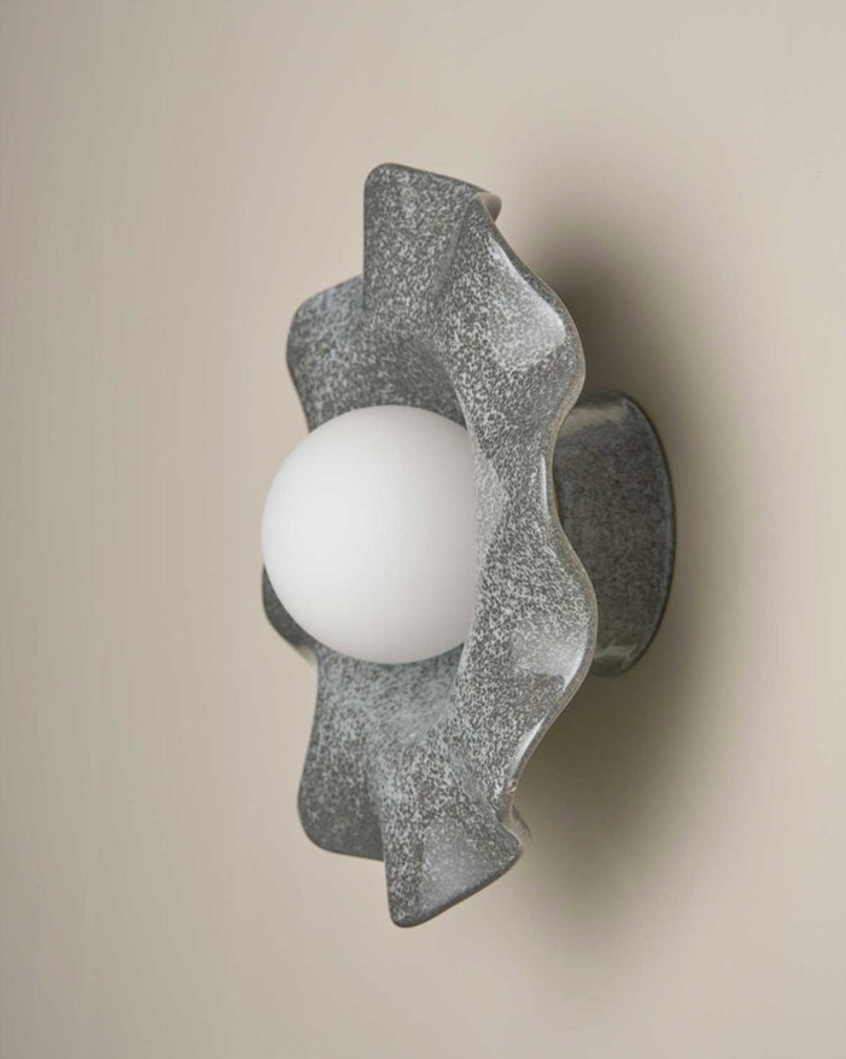 Decorative ceramic wall light fixture with a textured finish on a beige background
