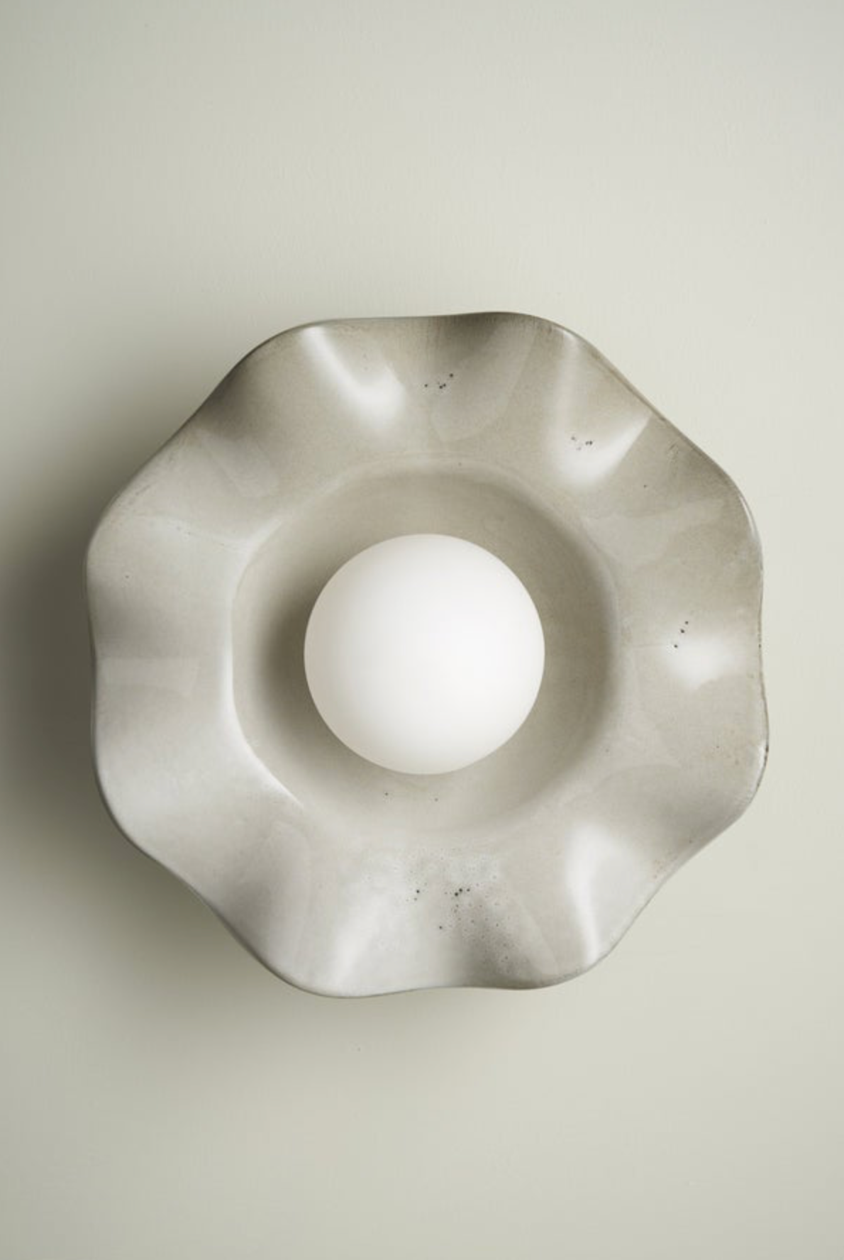 Decorative ceramic interior wall light fixture with a unique geometric design on a plain background