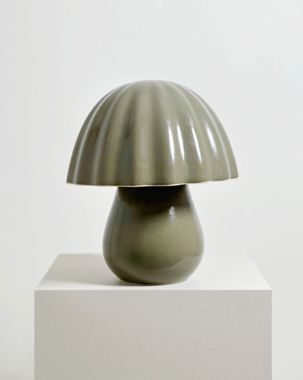 Mushroom-shaped ceramic lamp on a white pedestal against a light background