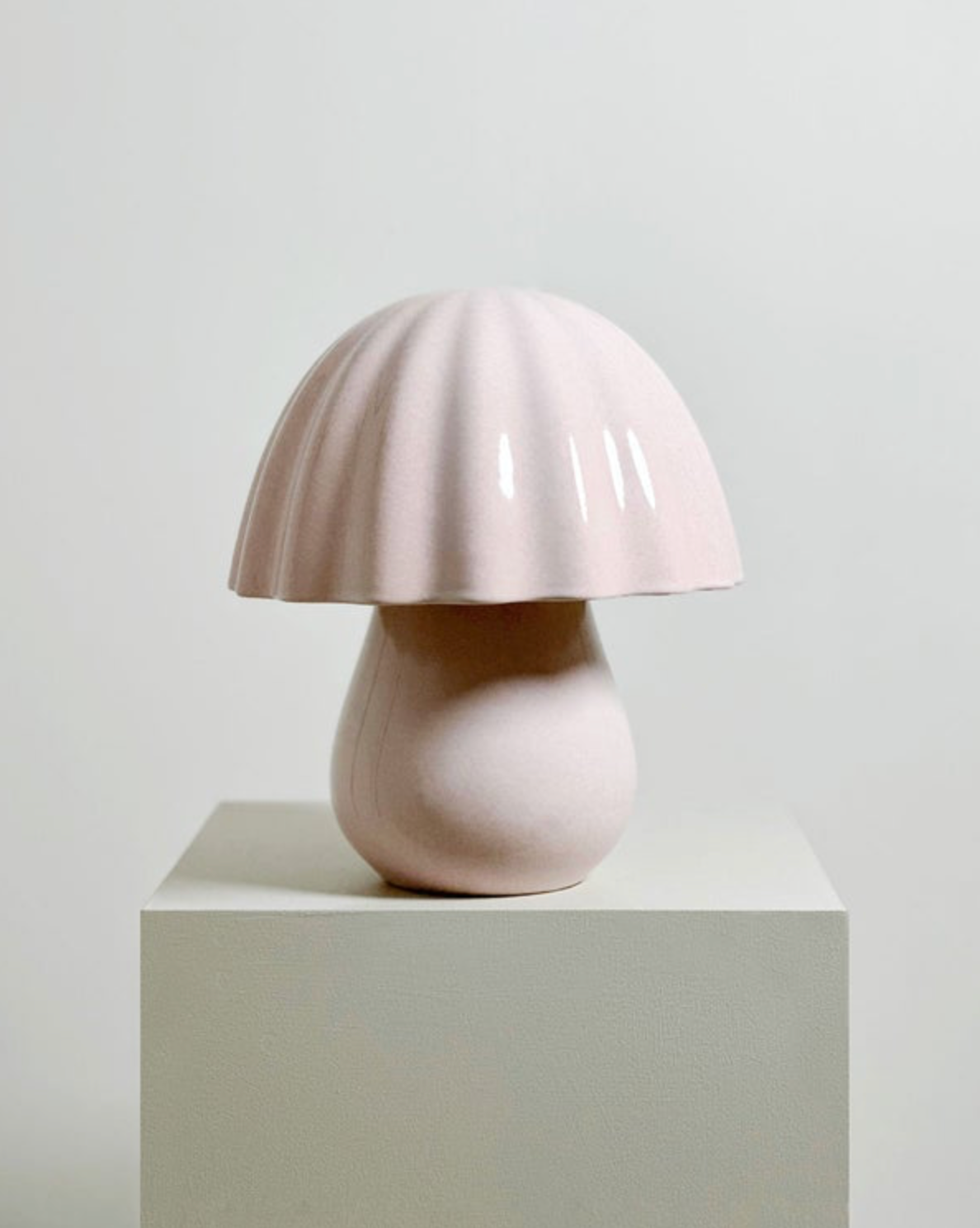 Pink ceramic lamp on a white pedestal against a light gray background