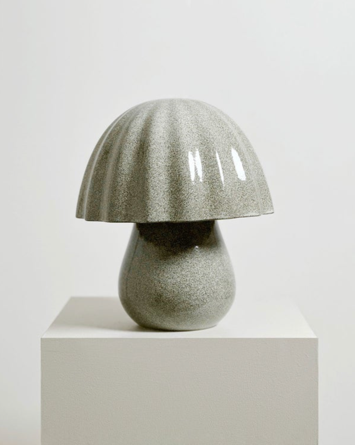 Mushroom-shaped ceramic lamp on a white pedestal against a light grey background