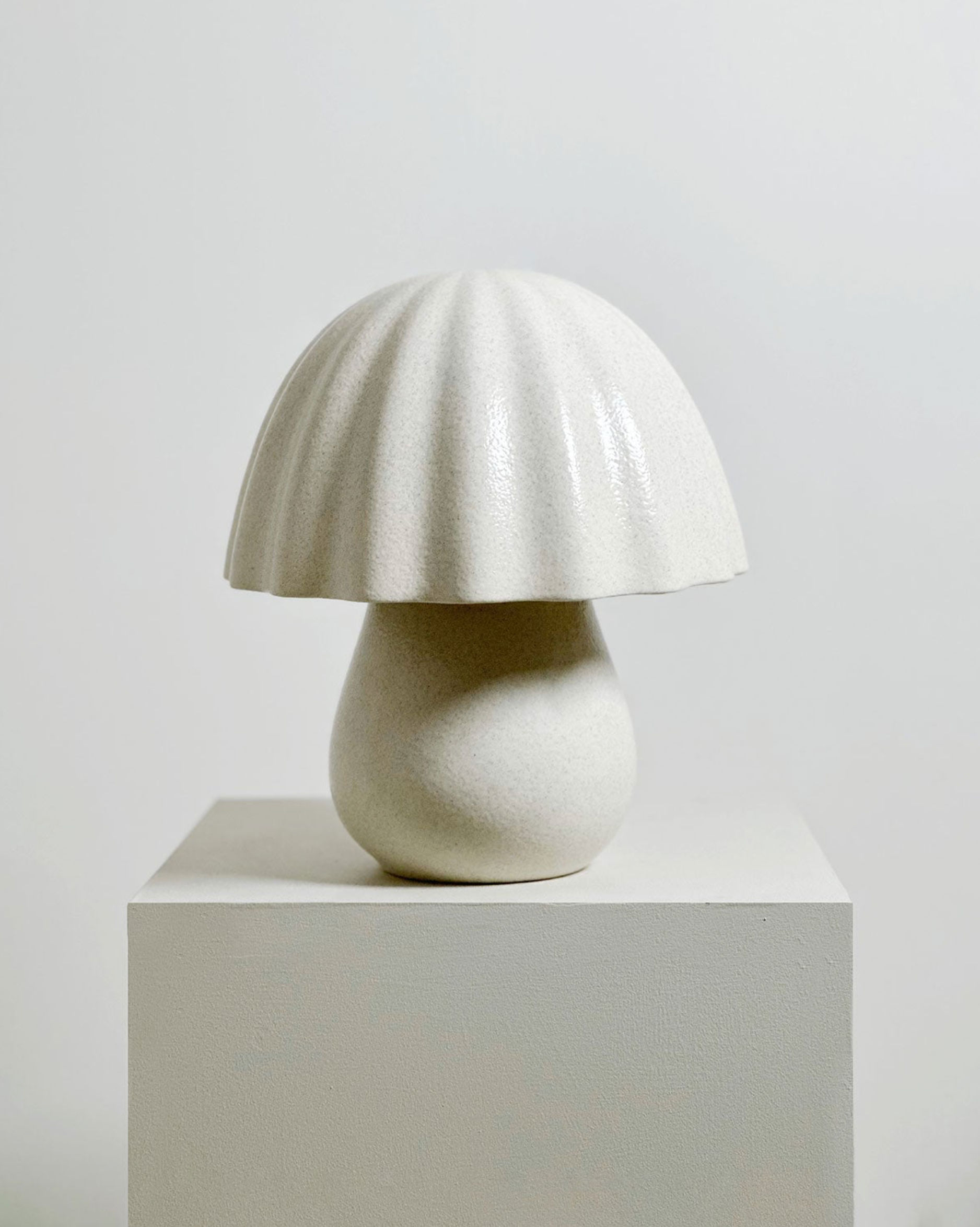 White ceramic lamp on a pedestal against a light gray background