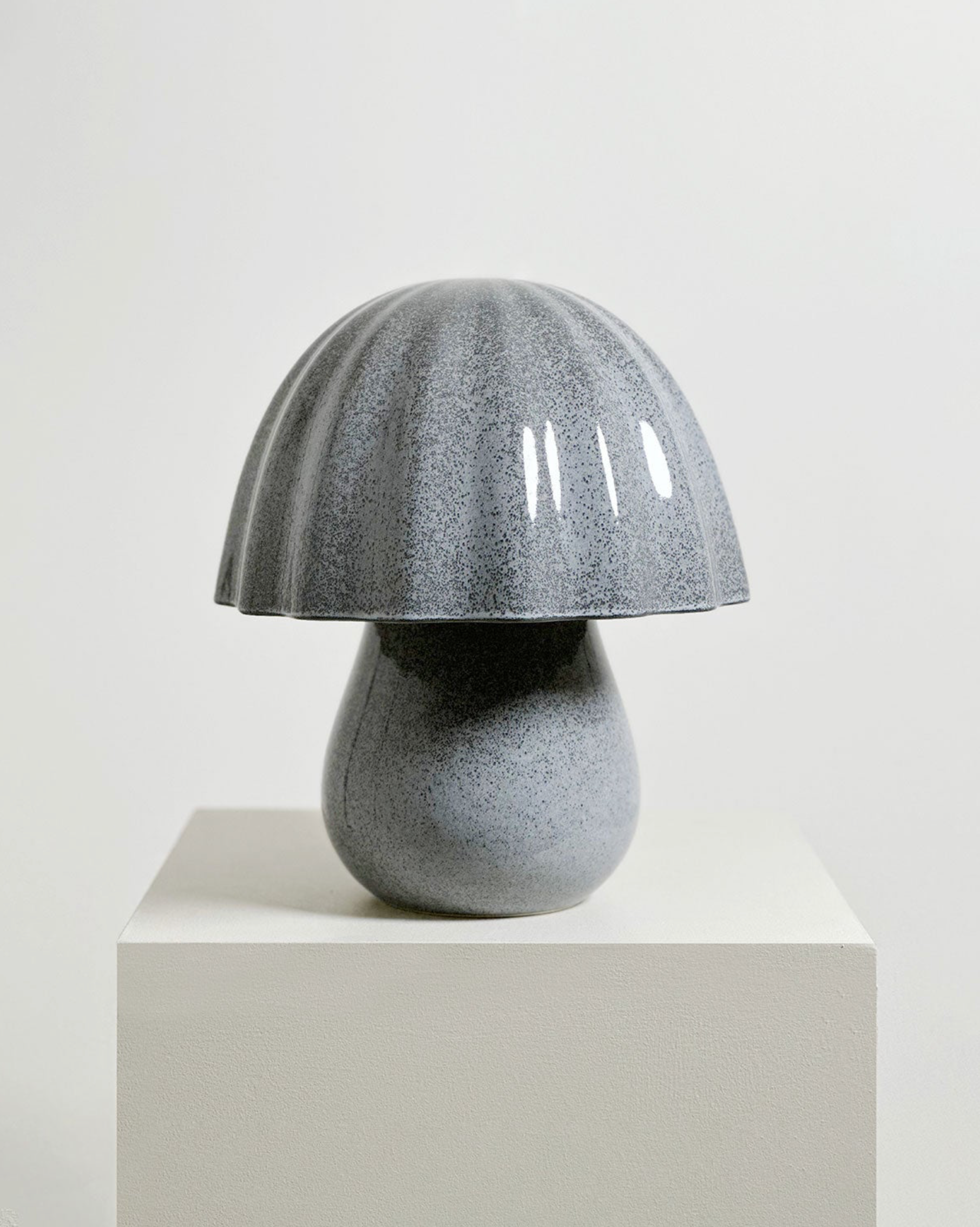 Ceramic mushroom-shaped lamp on a white pedestal against a light background