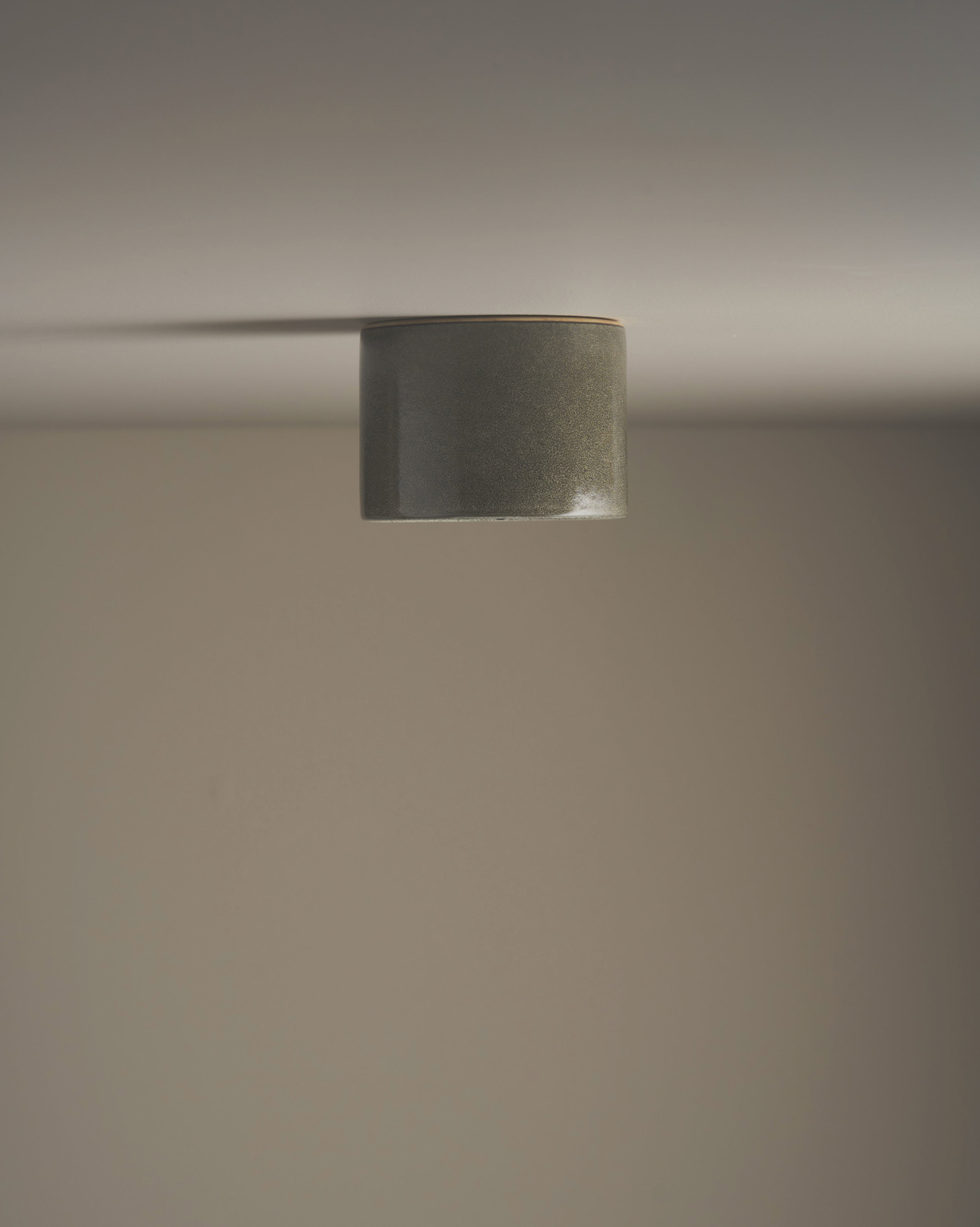 Close-up of a ceramic cylindrical light fixture on a neutral background