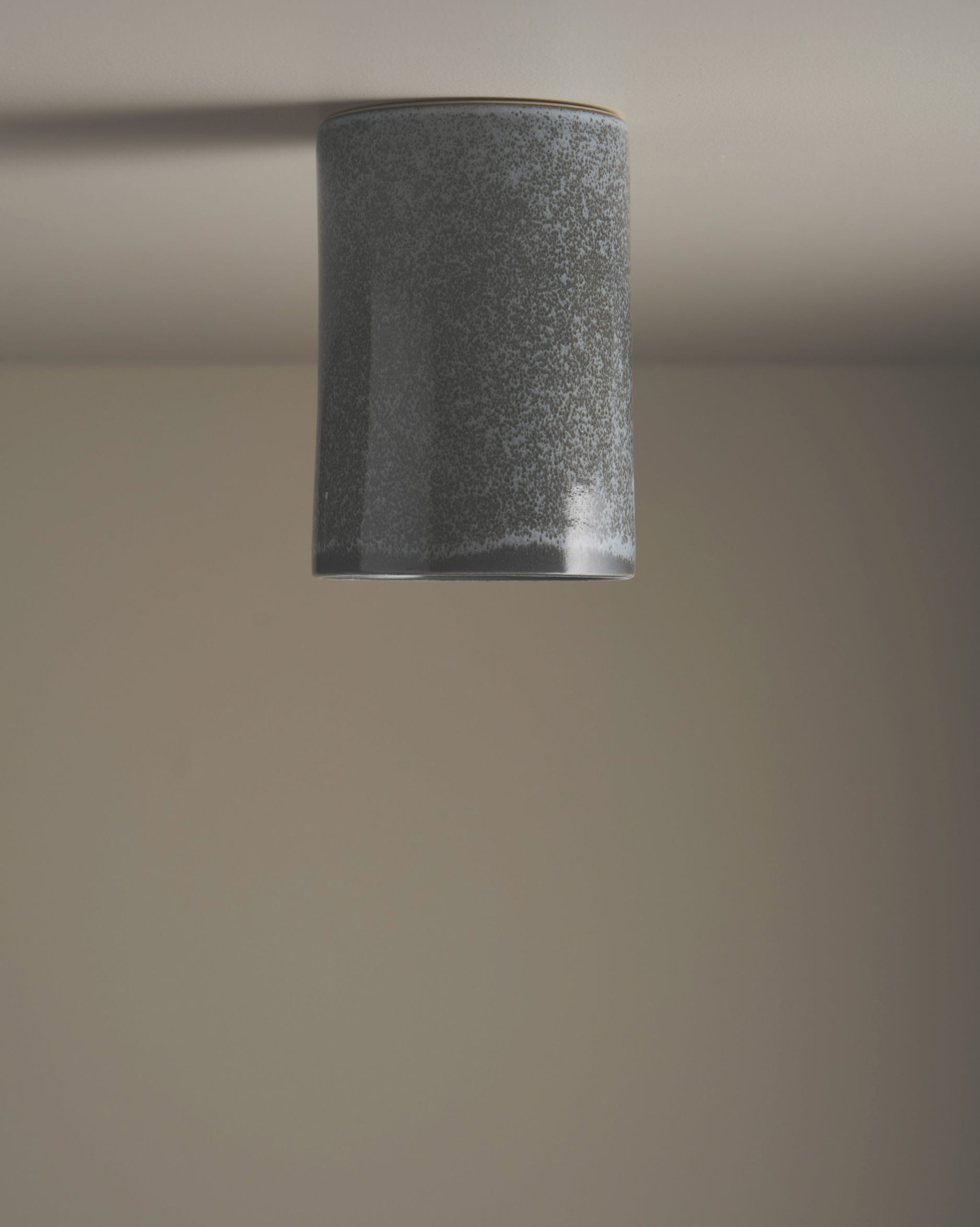 Cylindrical ceramic ceiling light fixture on a plain ceiling