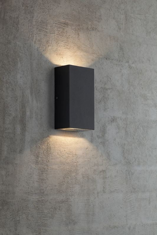 Black square outdoor wall light fixture on a textured grey wall