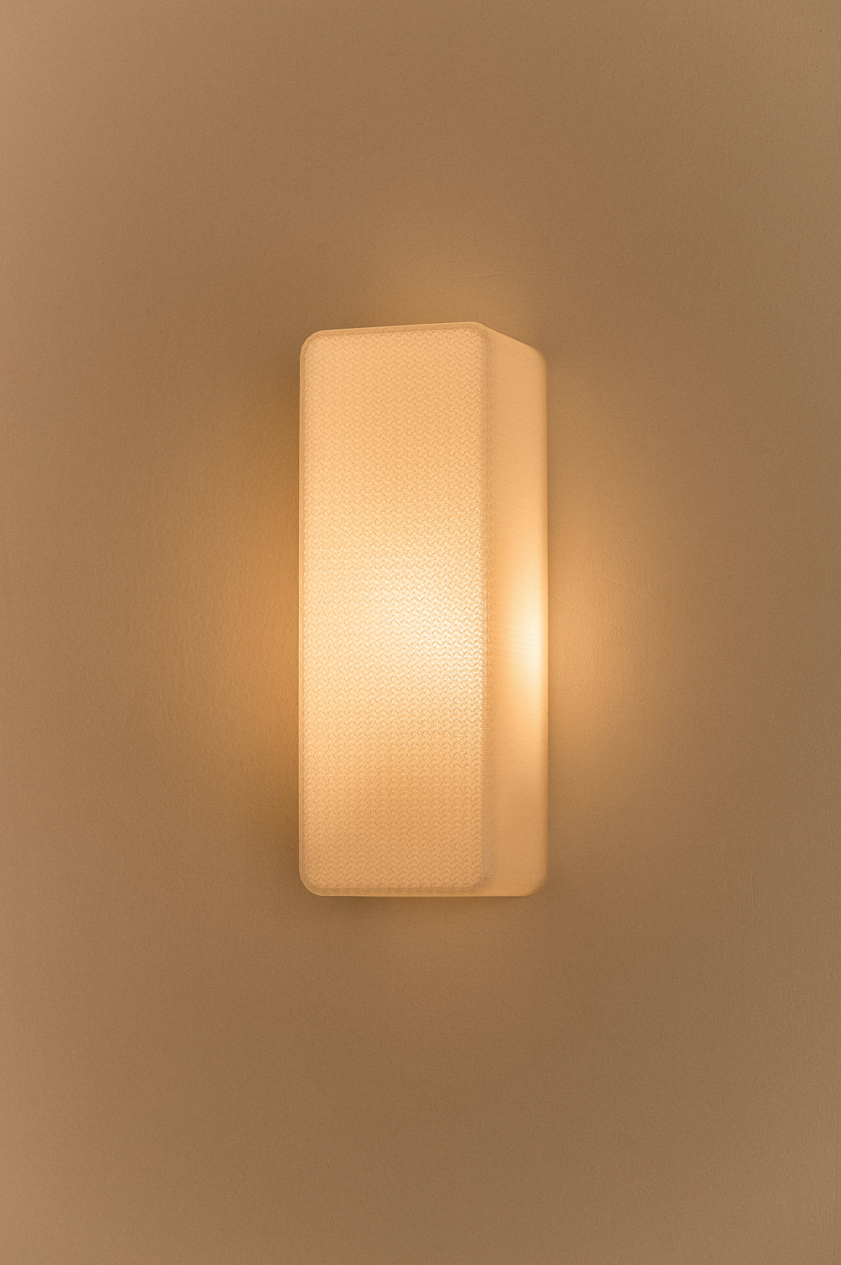 Rectangular 3D printed wall light fixture on a beige wall