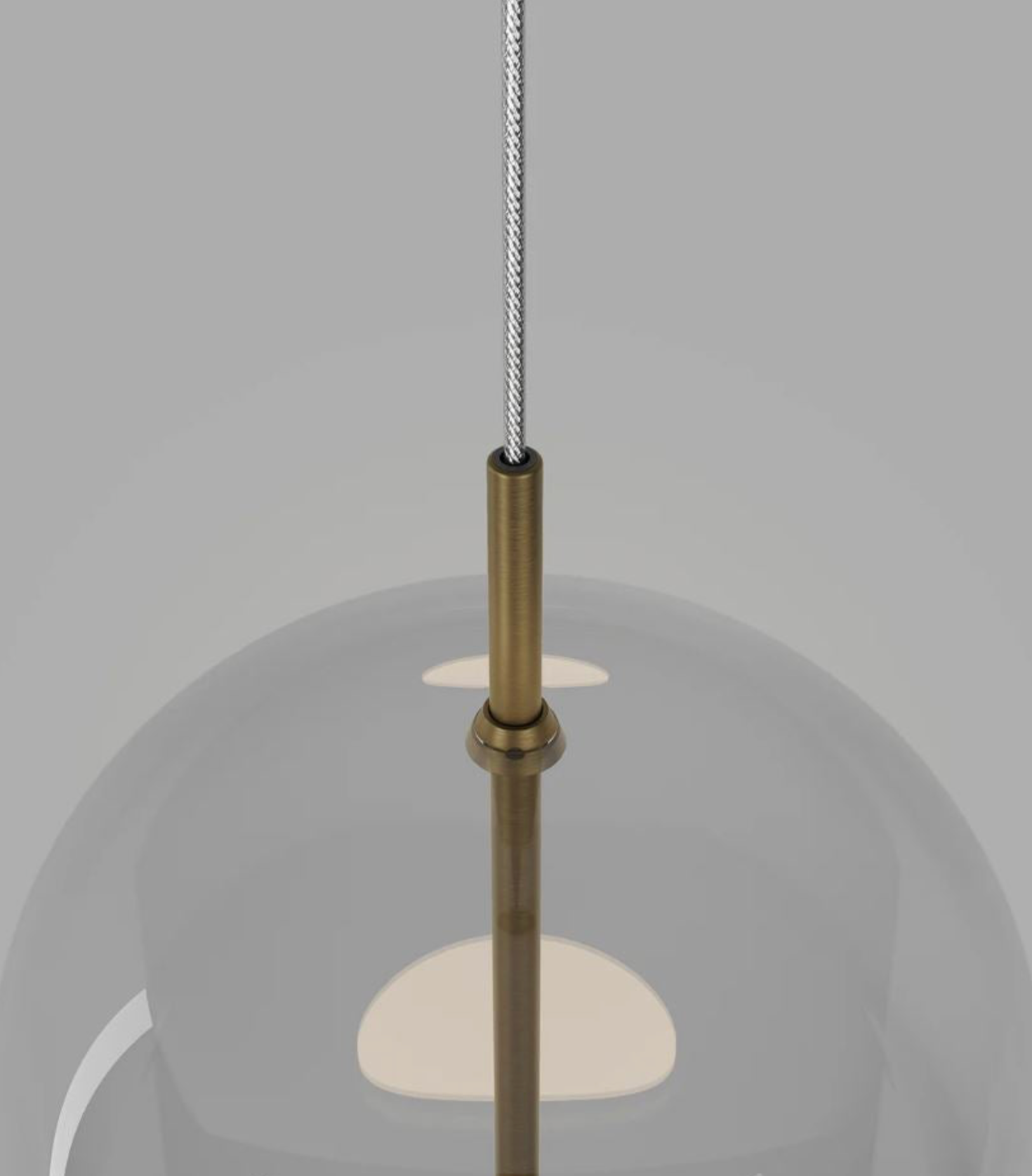 Pendant light with glass shade and brass fixture on a grey background