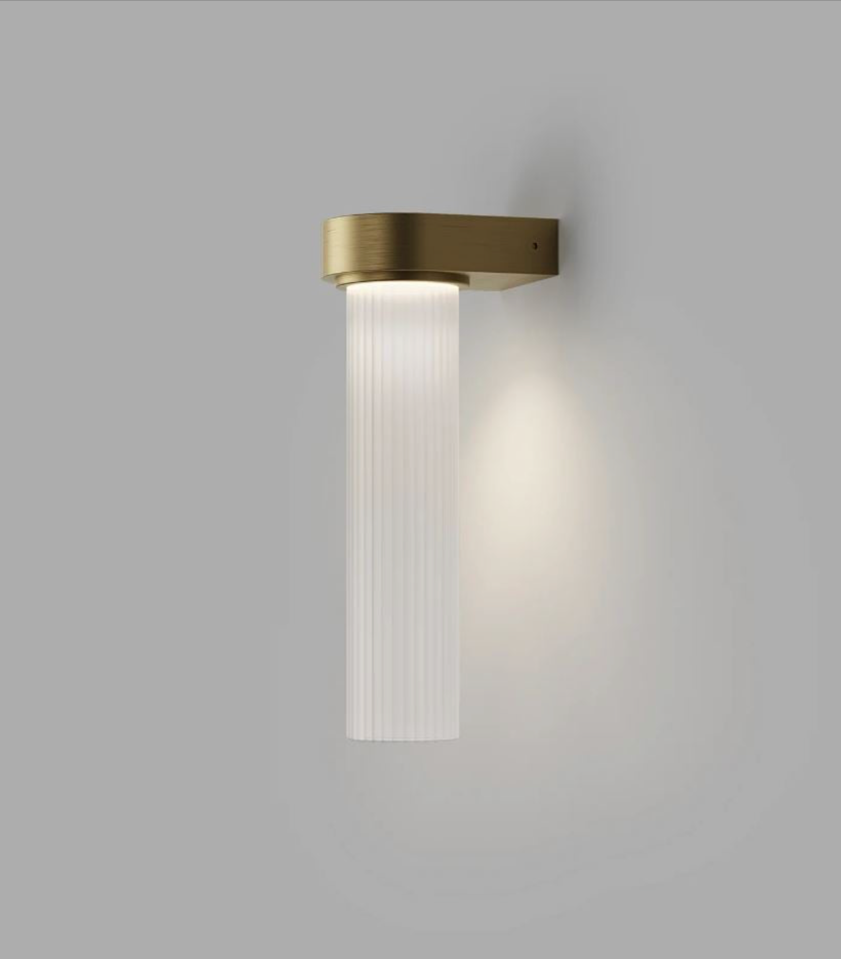 Wall-mounted light fixture with brass finish and ribbed glass on a grey background