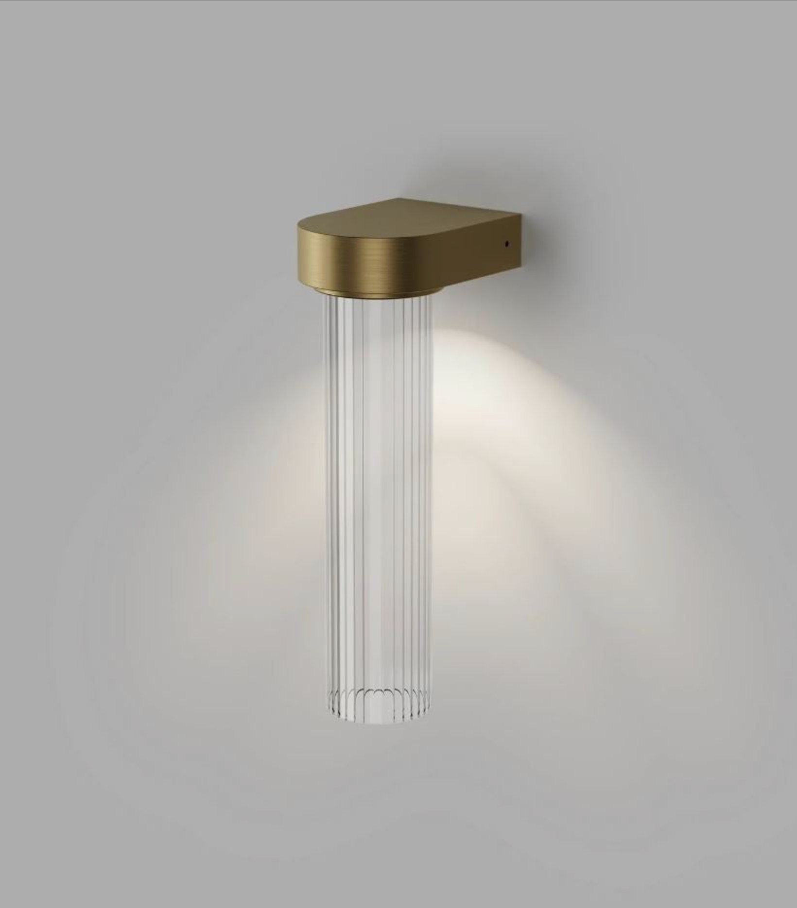 Wall-mounted light fixture with brass finish and clear glass on a grey background