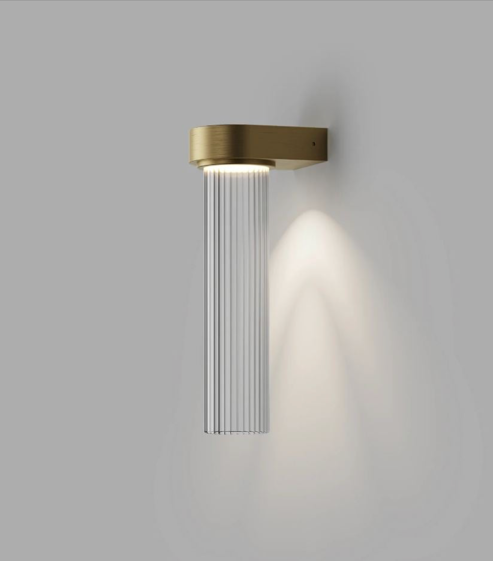 Modern wall-mounted light fixture with brass finish on a grey background