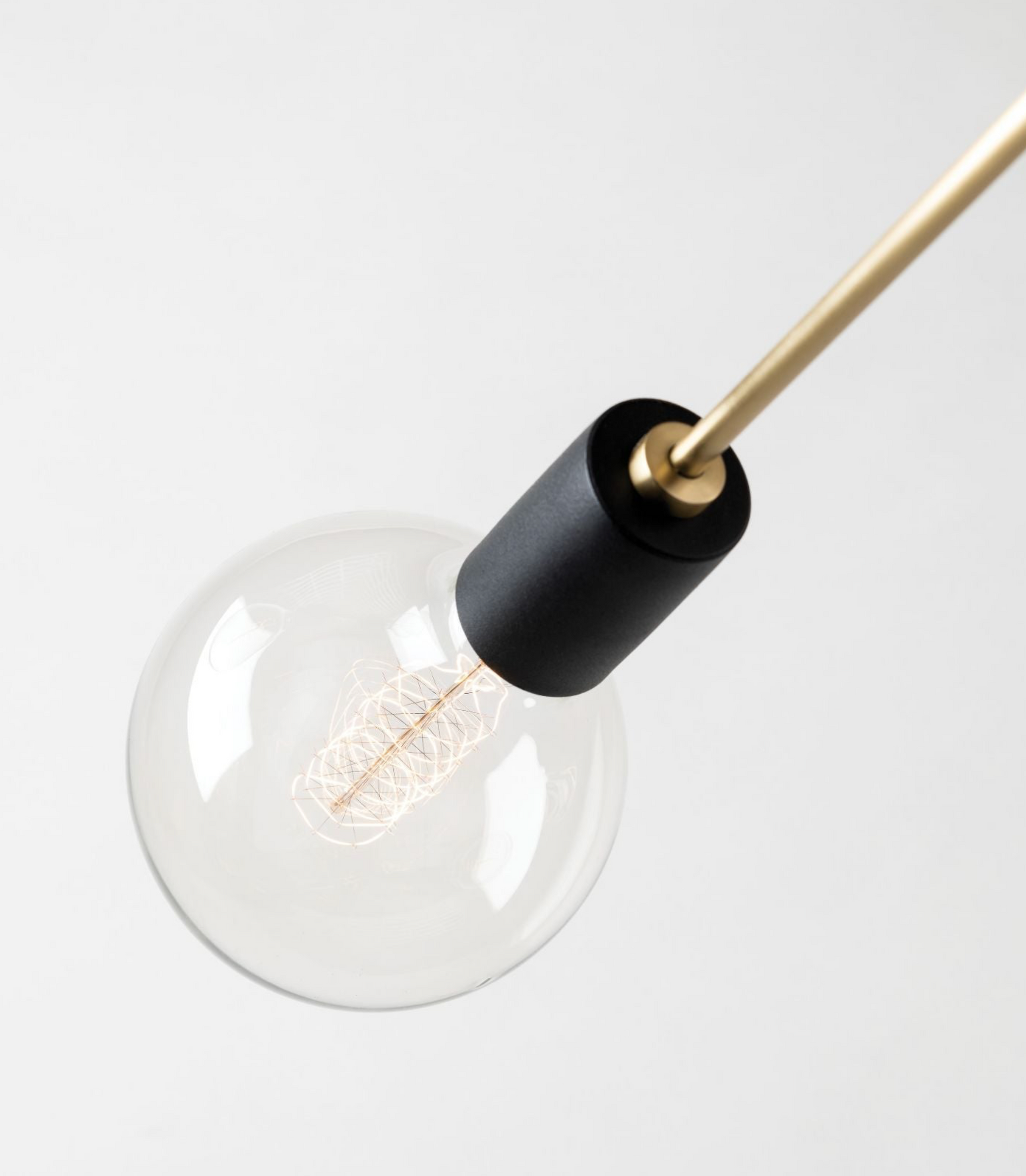 Clear light bulb with black base and gold fixture on a white background