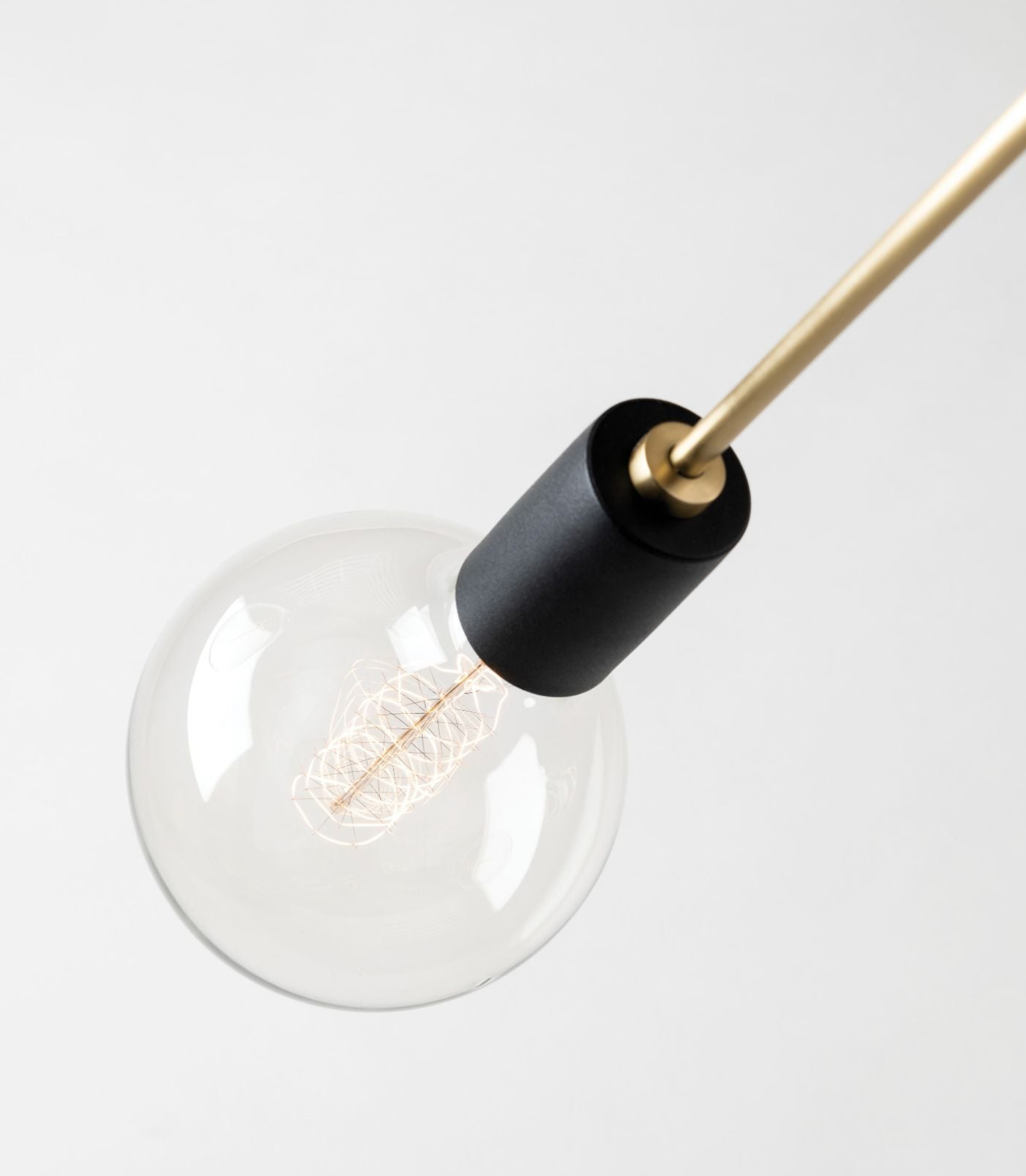 Clear light bulb with black base and gold fixture on a white background