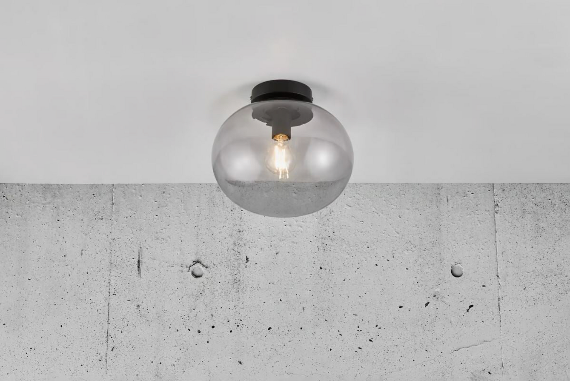 Ceiling light fixture with glass shade on a concrete wall background