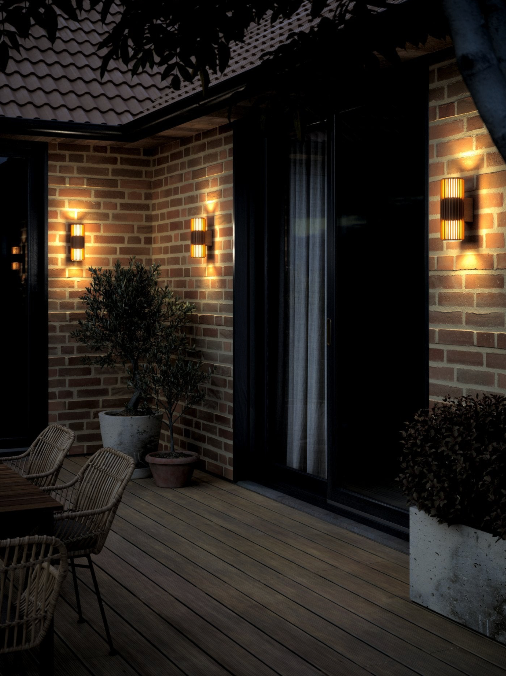 Outdoor patio area with brick wall, wooden deck, and wall-mounted lights.