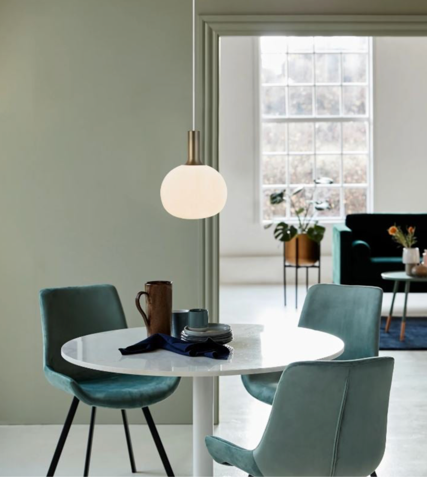 Dining area with a round table and chairs, featuring a white glass pendant light.
