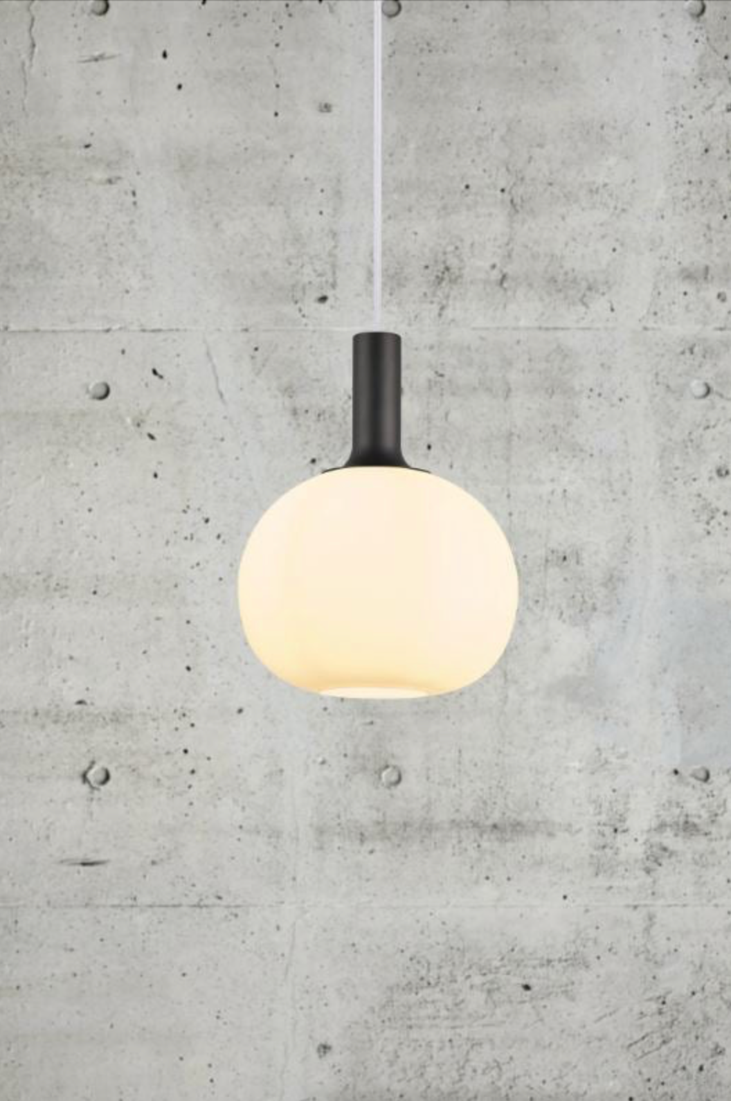 Pendant light with a  black fixture against a concrete wall.