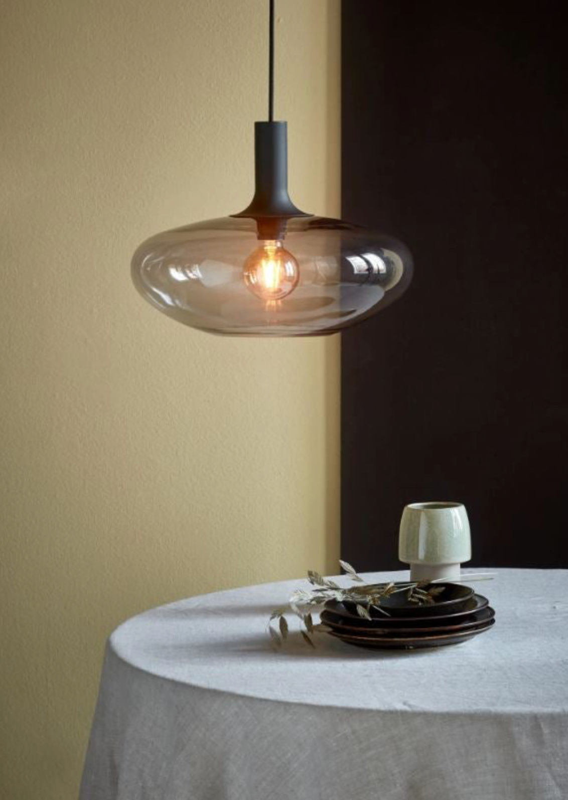 Pendant light fixture hanging above a table with a dark wall background