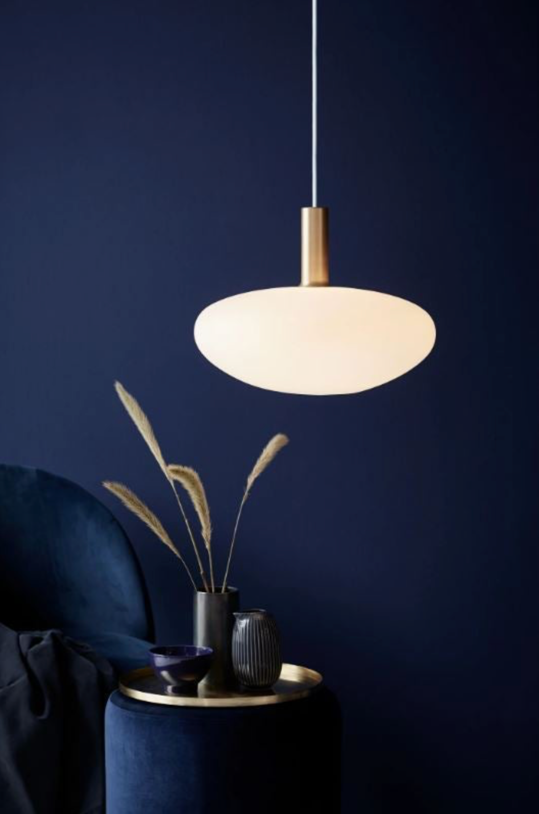 Pendant light fixture hanging above a dark blue wall with decorative elements.