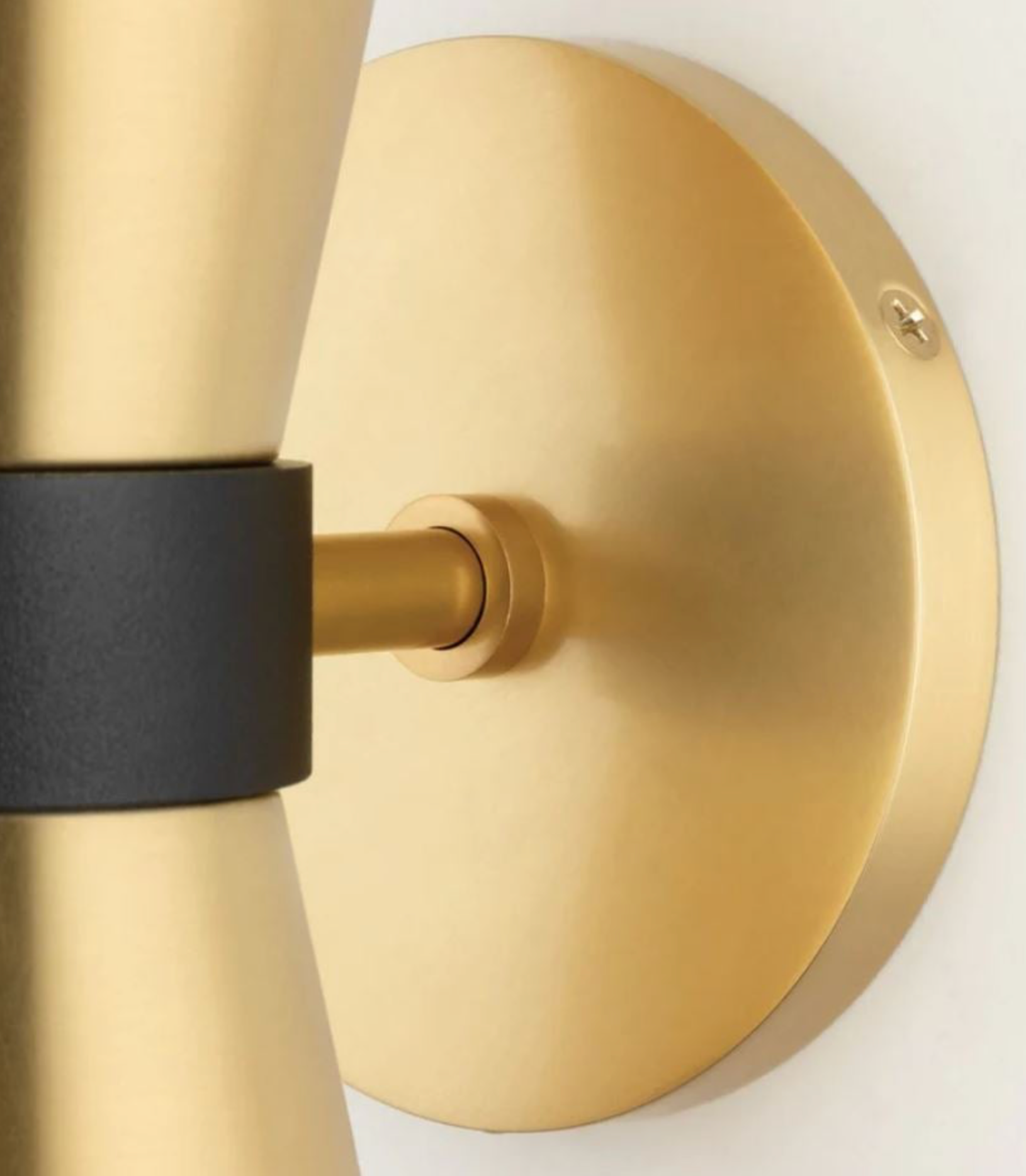 Gold wall sconce with black accent on a white background