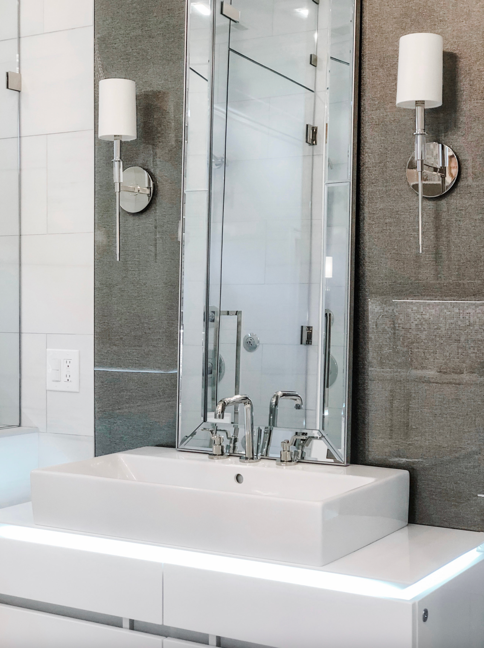 Modern bathroom with a sink, mirror, and wall lights.