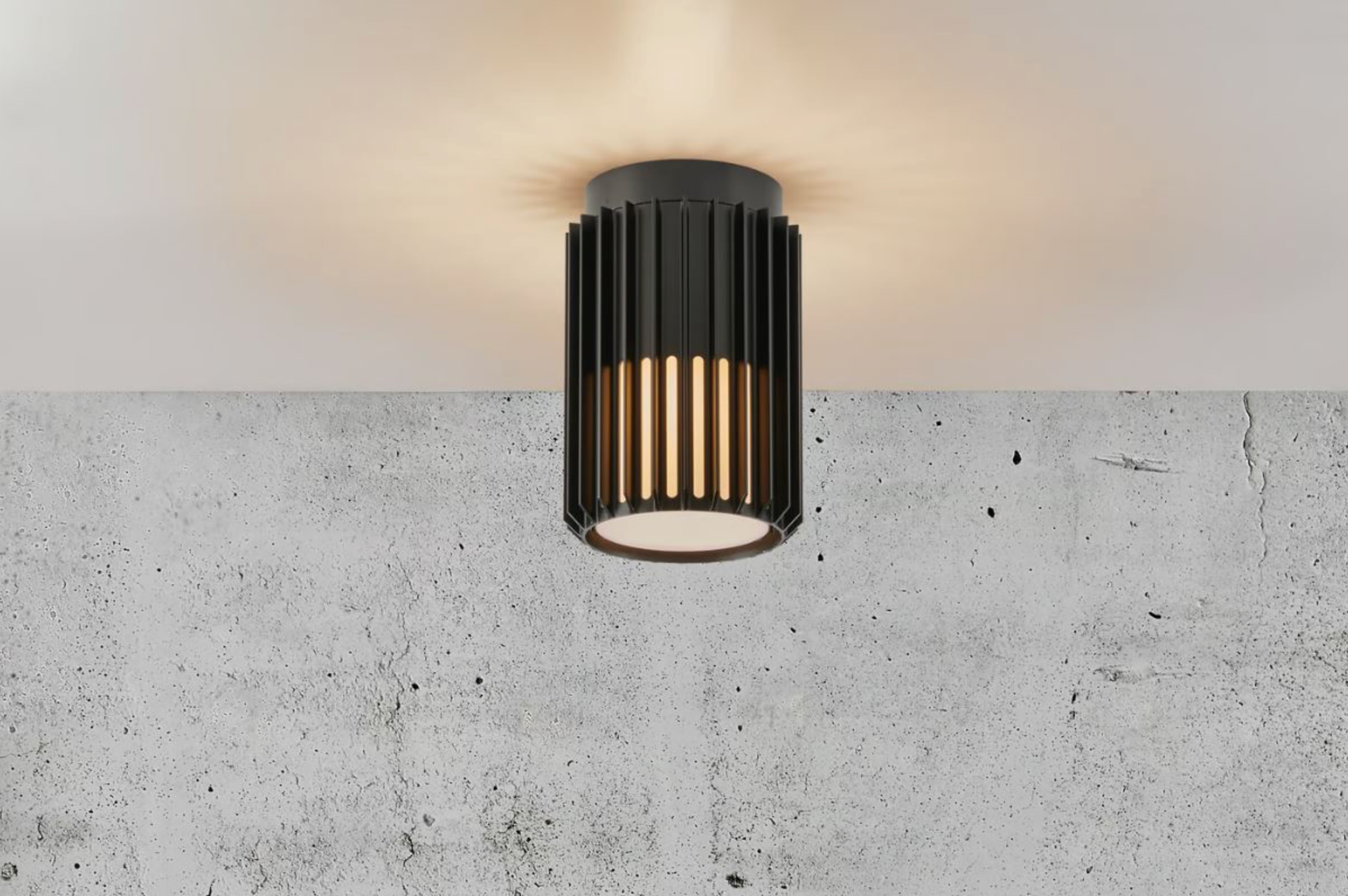 Black cylindrical outdoor ceiling light fixture on a concrete wall