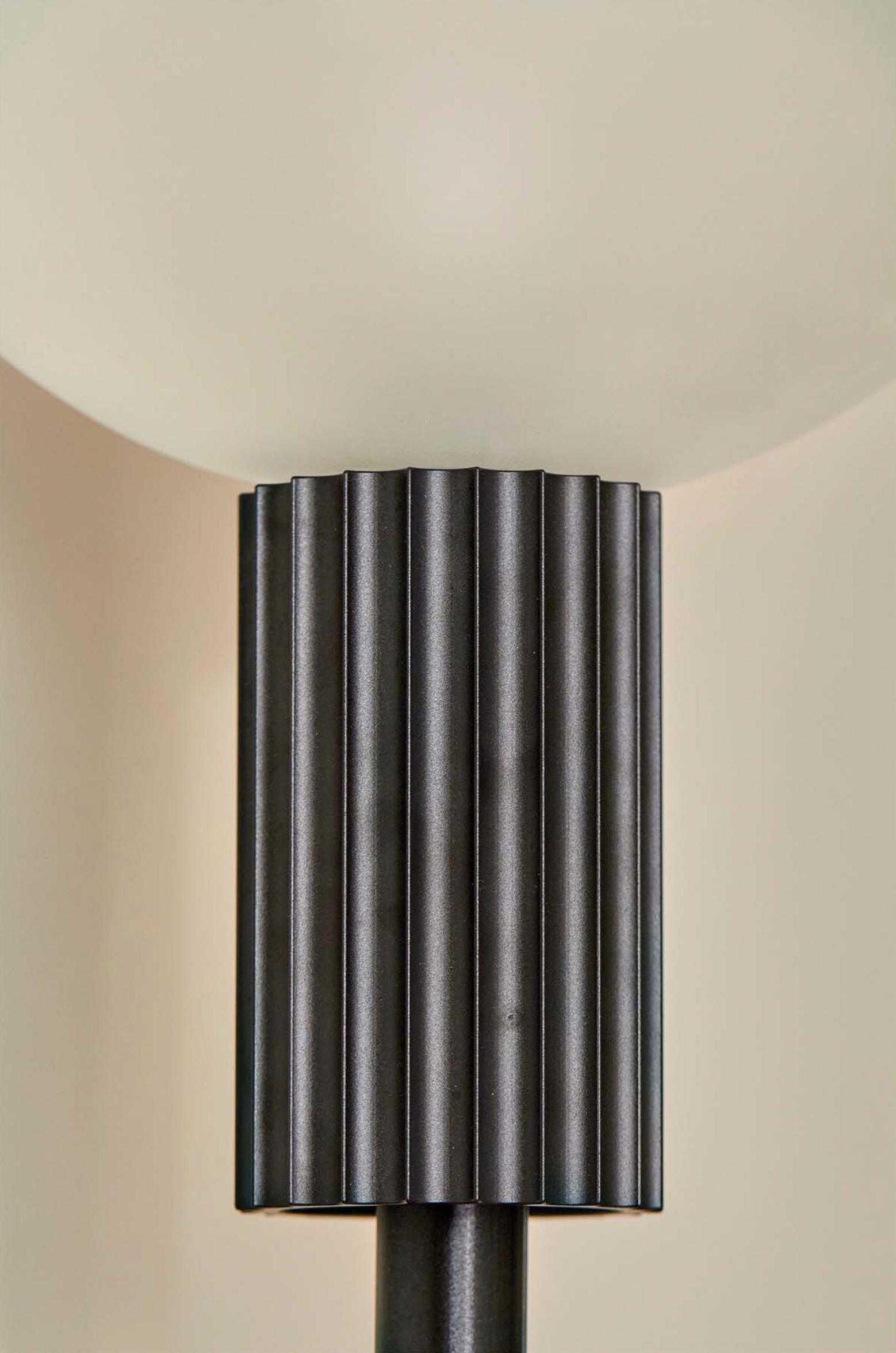 Decorative cylindrical light fixture with ribbed design on a beige background