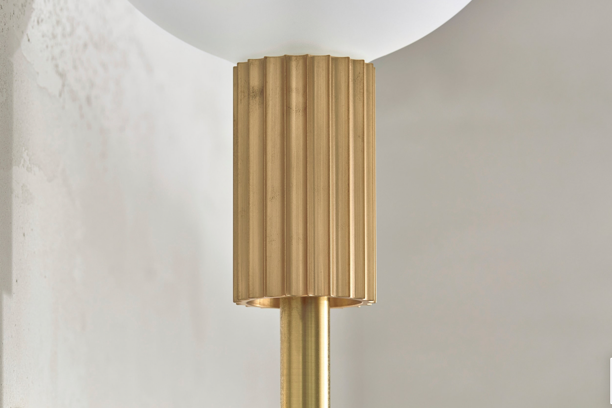 Modern indoor wall light fixture with brass finish on a neutral background