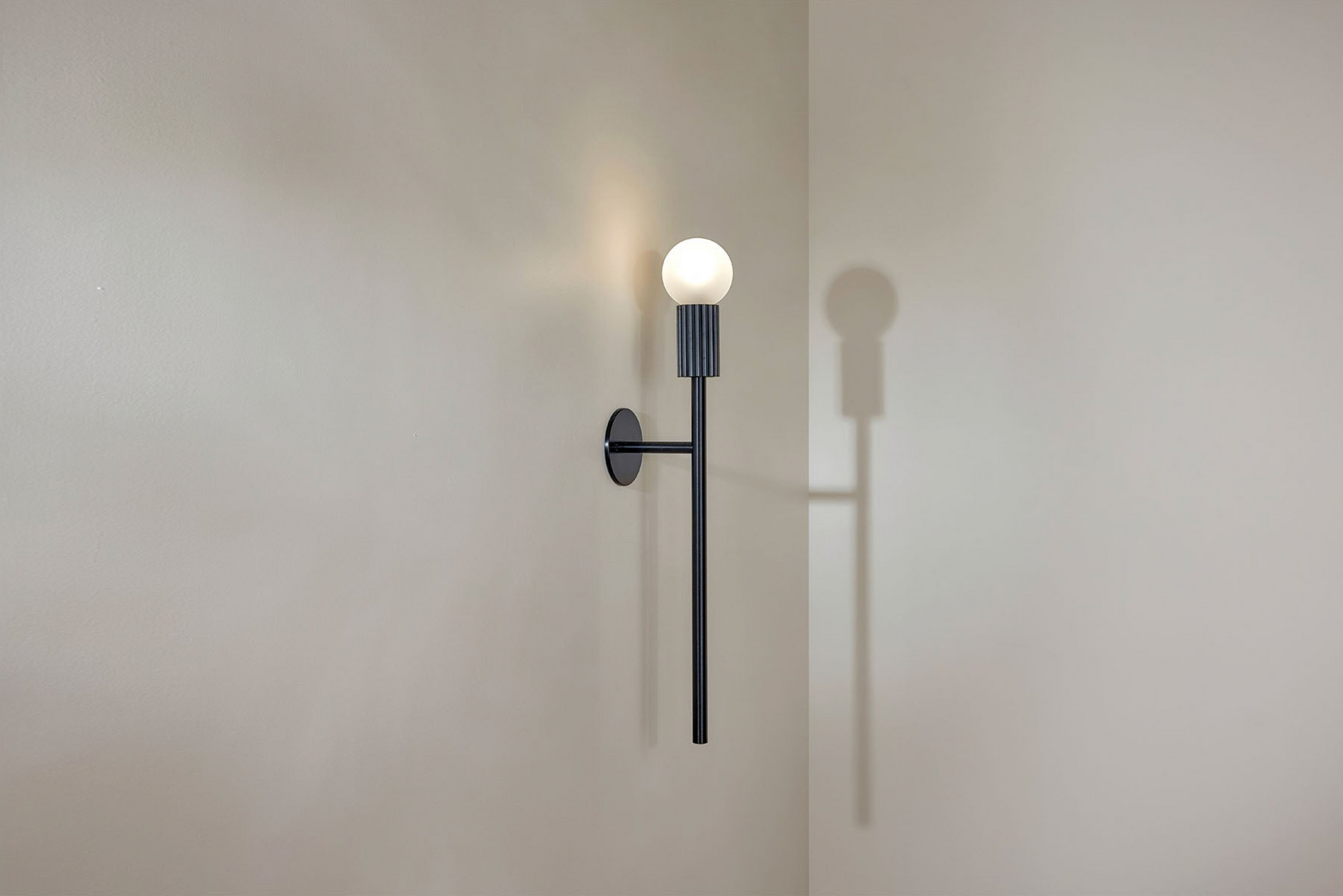 Wall-mounted light fixture casting a shadow on a plain wall