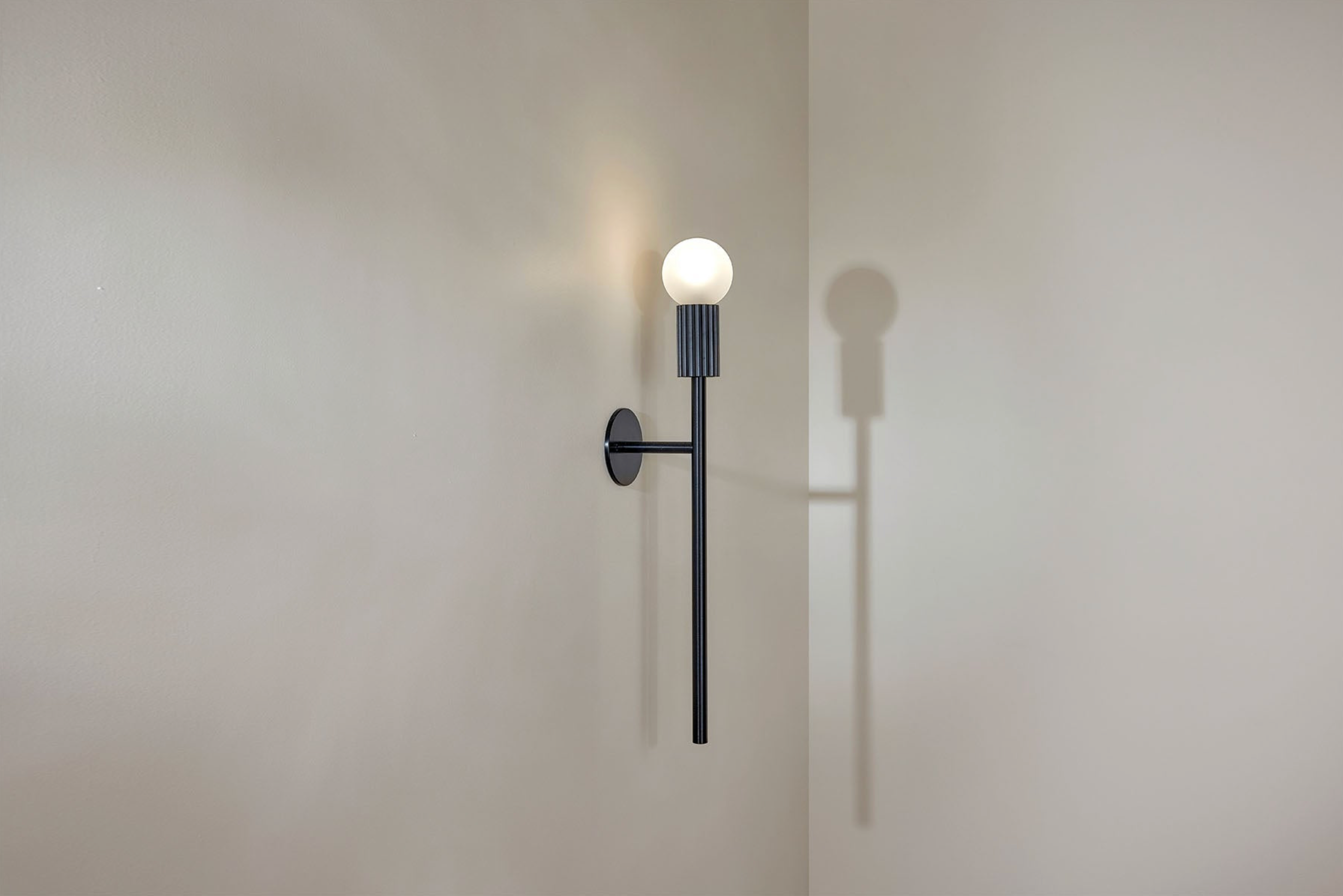 Wall-mounted light fixture casting a shadow on a plain wall