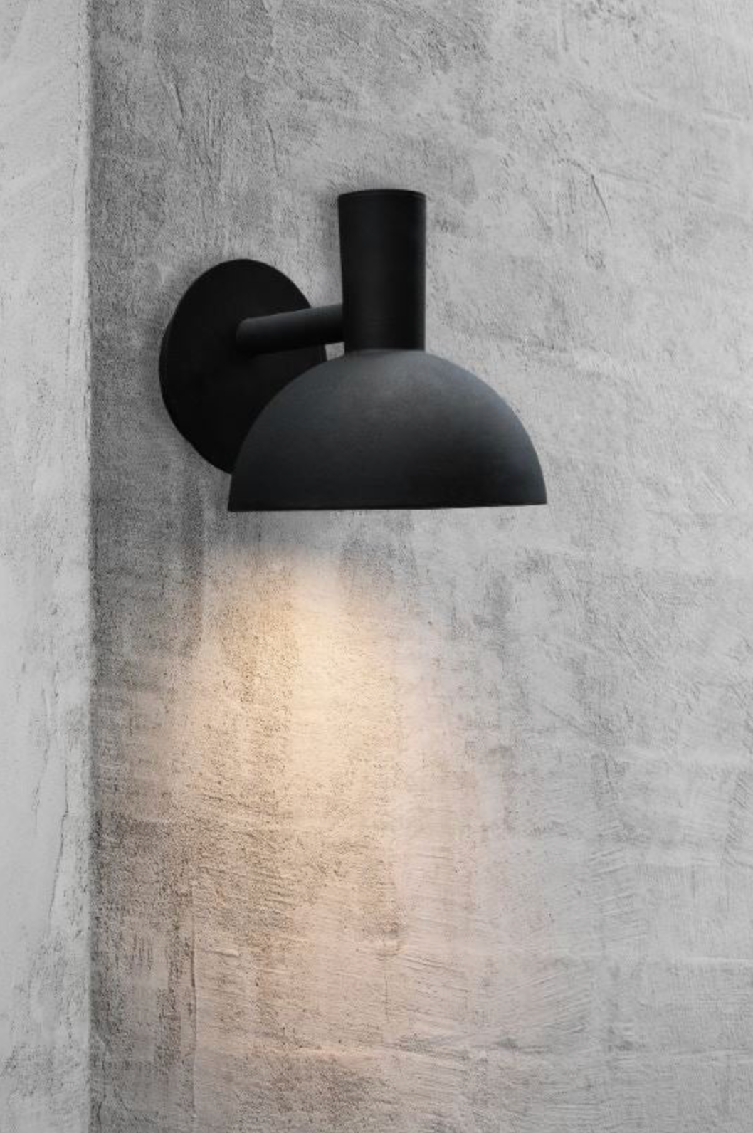 Black outdoor wall-mounted light fixture on a concrete wall