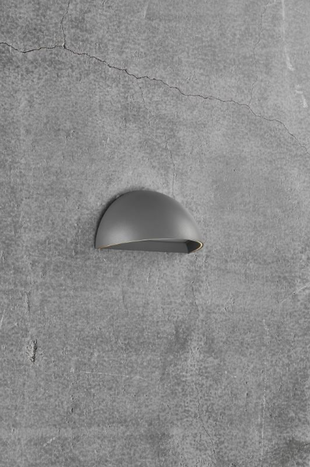 Grey wall-mounted outdoor light fixture on a concrete wall.