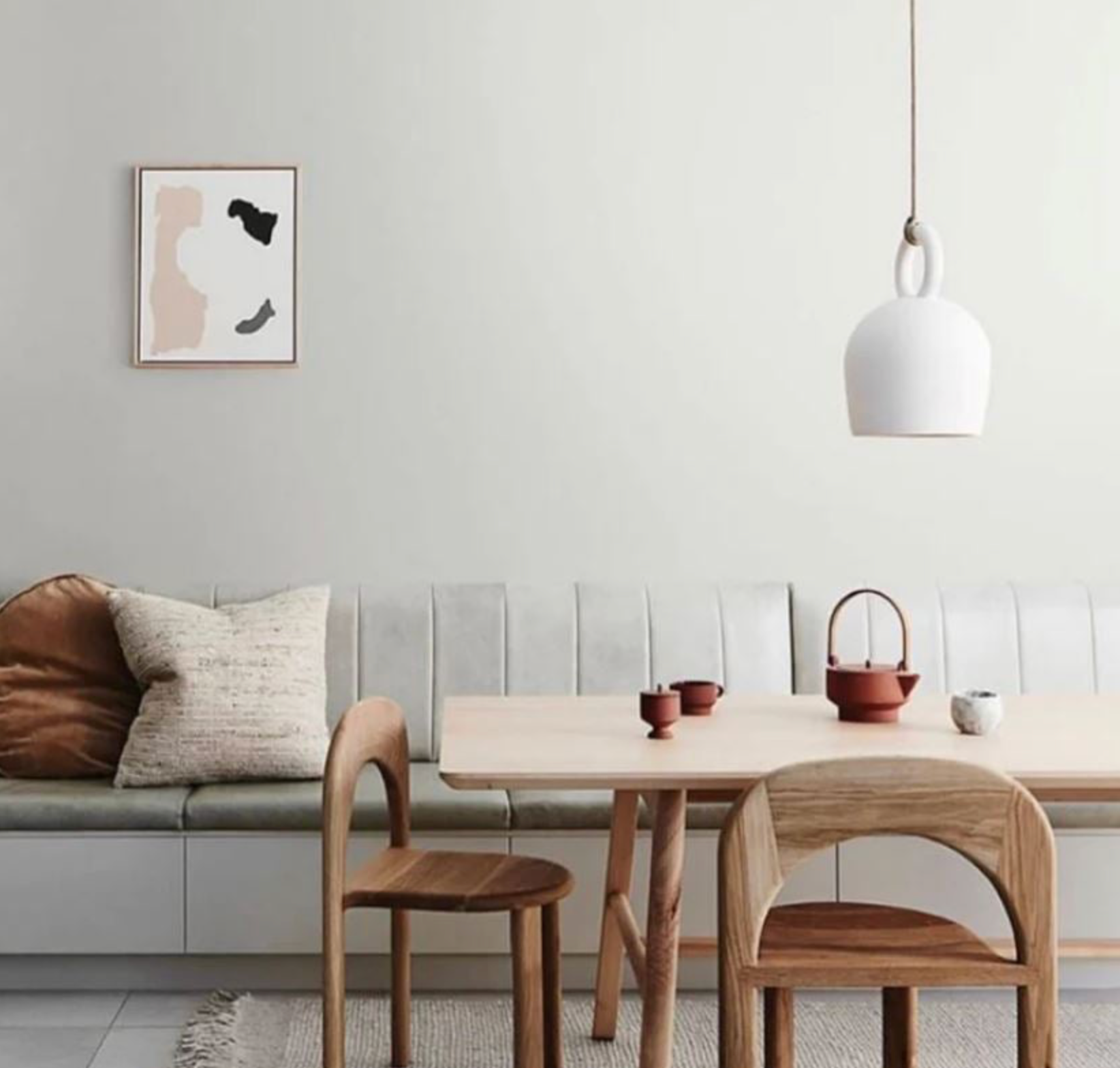 Modern living room with wooden furniture and a white pendant light and white wall.