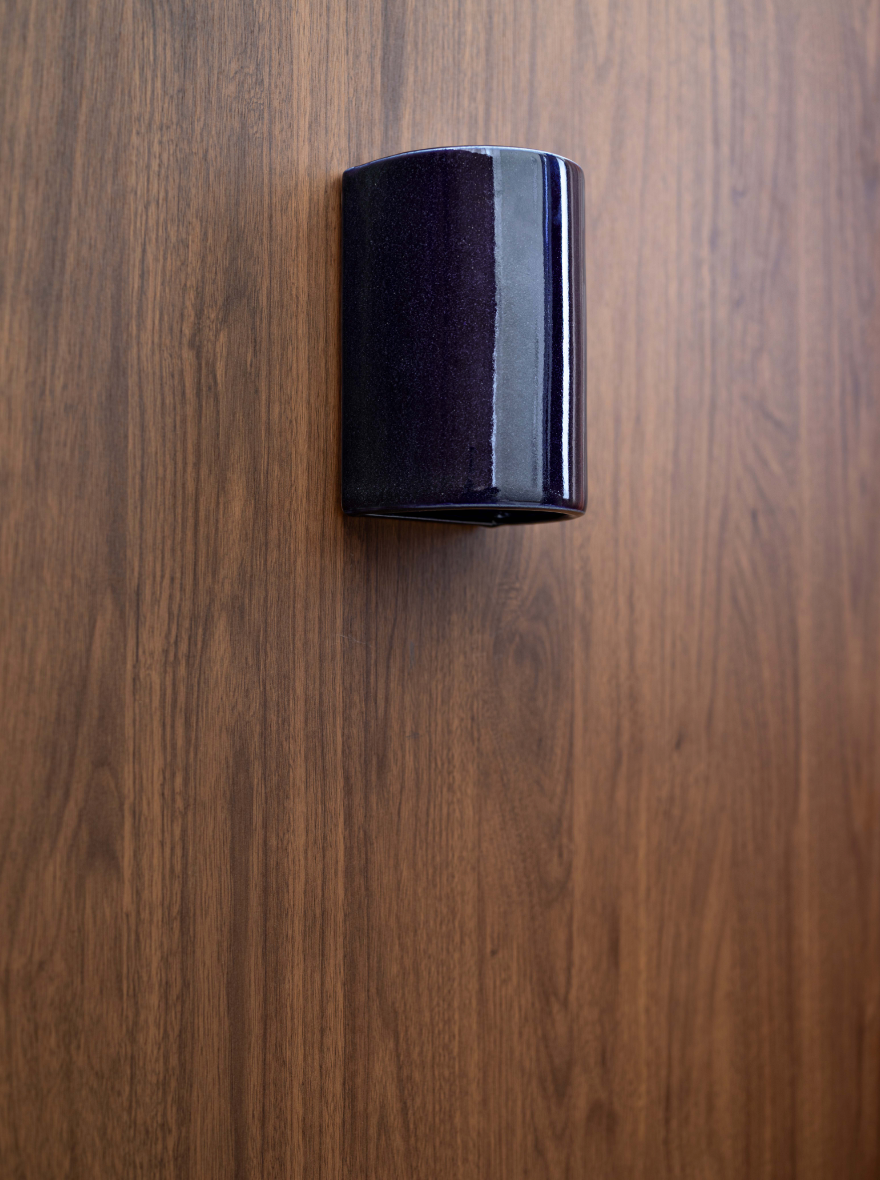 Glazed cylindrical outdoor wall light on a wooden surface