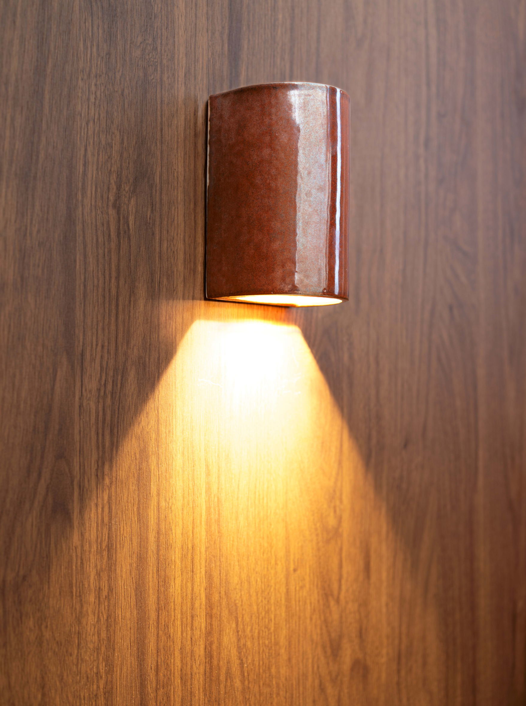 Wall-mounted glazed ceramic outdoor light fixture on a wooden wall
