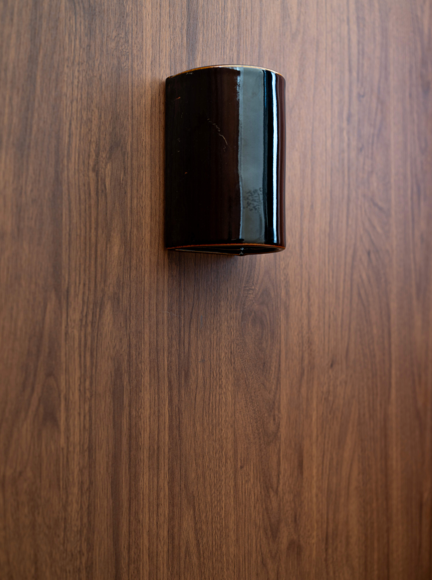 Black ceramic outdoor wall light on a wooden surface